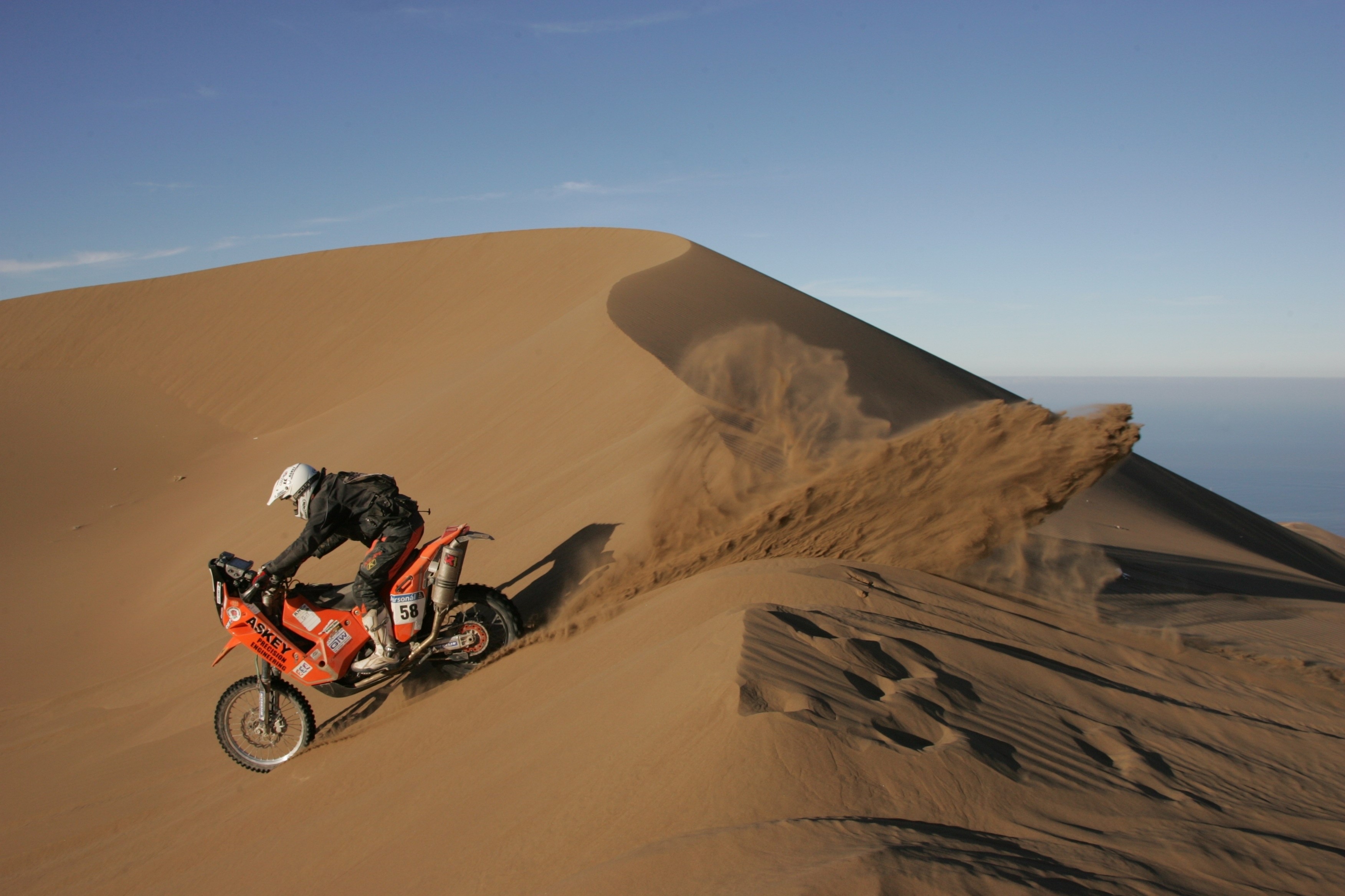 Motorcyclist racing on a sand dune HD Wallpaper