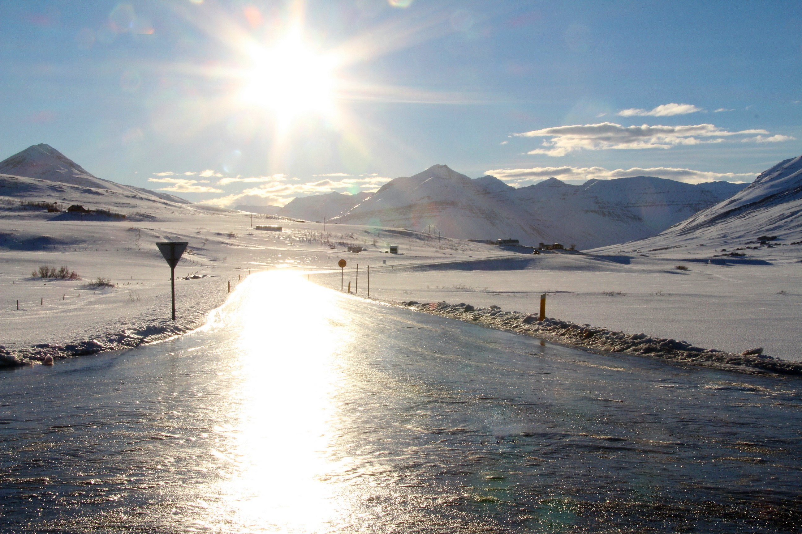 Sunlit icy road through snowy mountains in Iceland HD Wallpaper