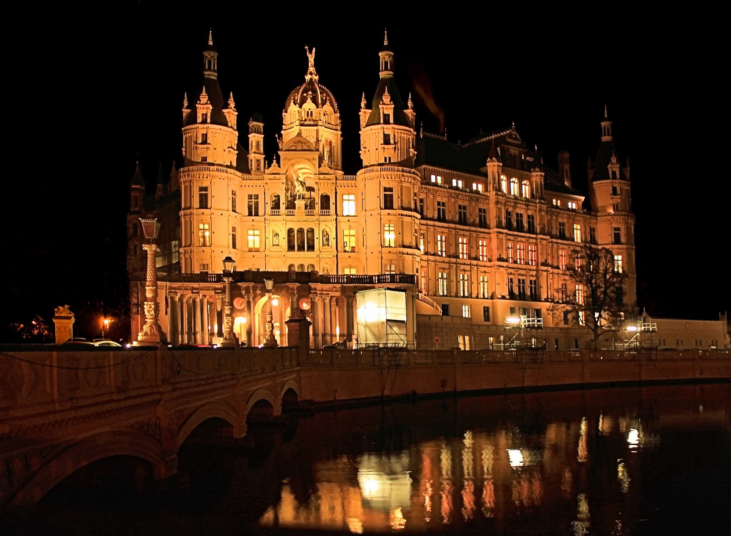 Schweriner Castle illuminated at night over a river HD Wallpaper