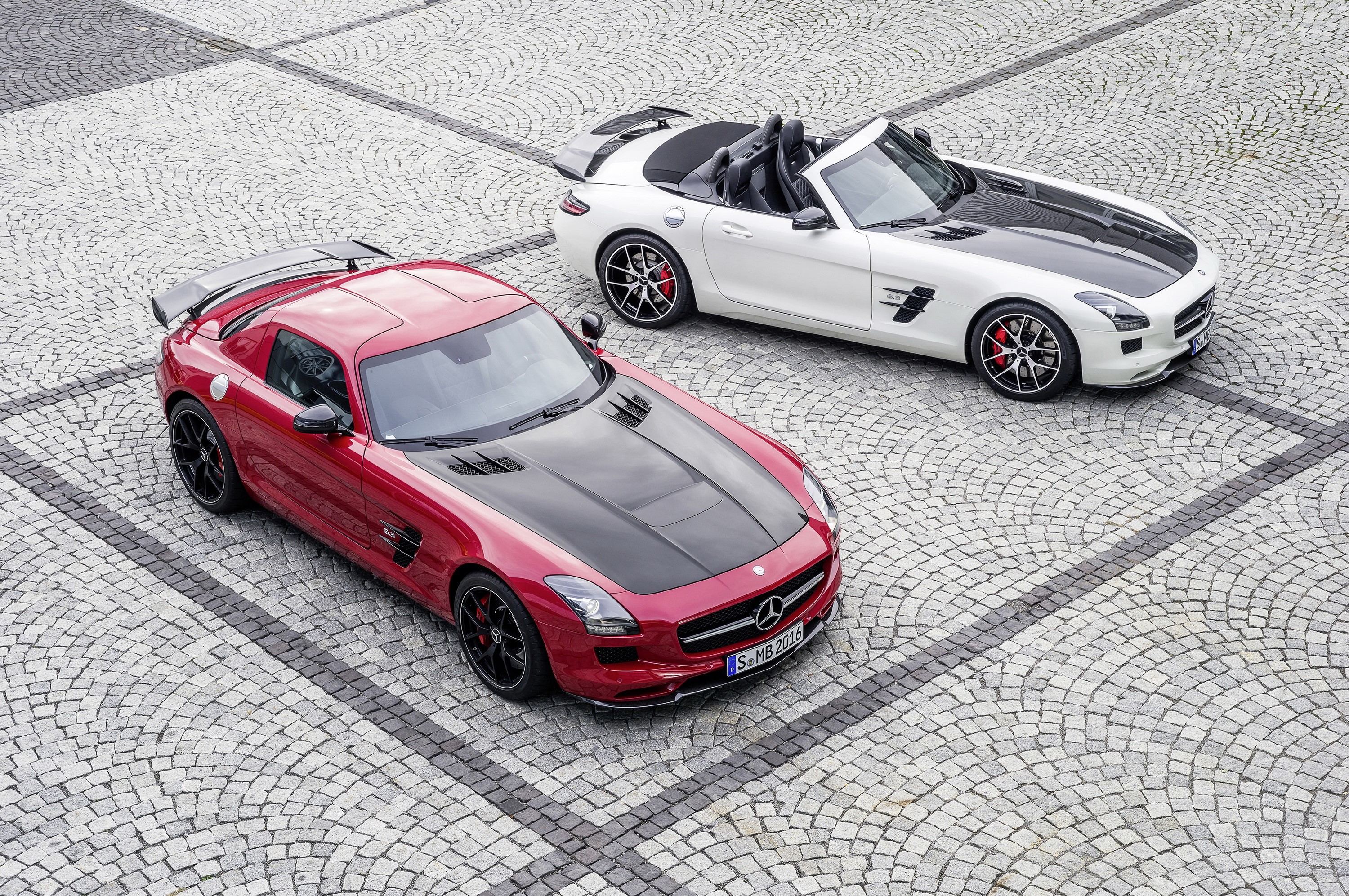 Two Mercedes-Benz SLS AMG GT cars on cobblestone HD Wallpaper
