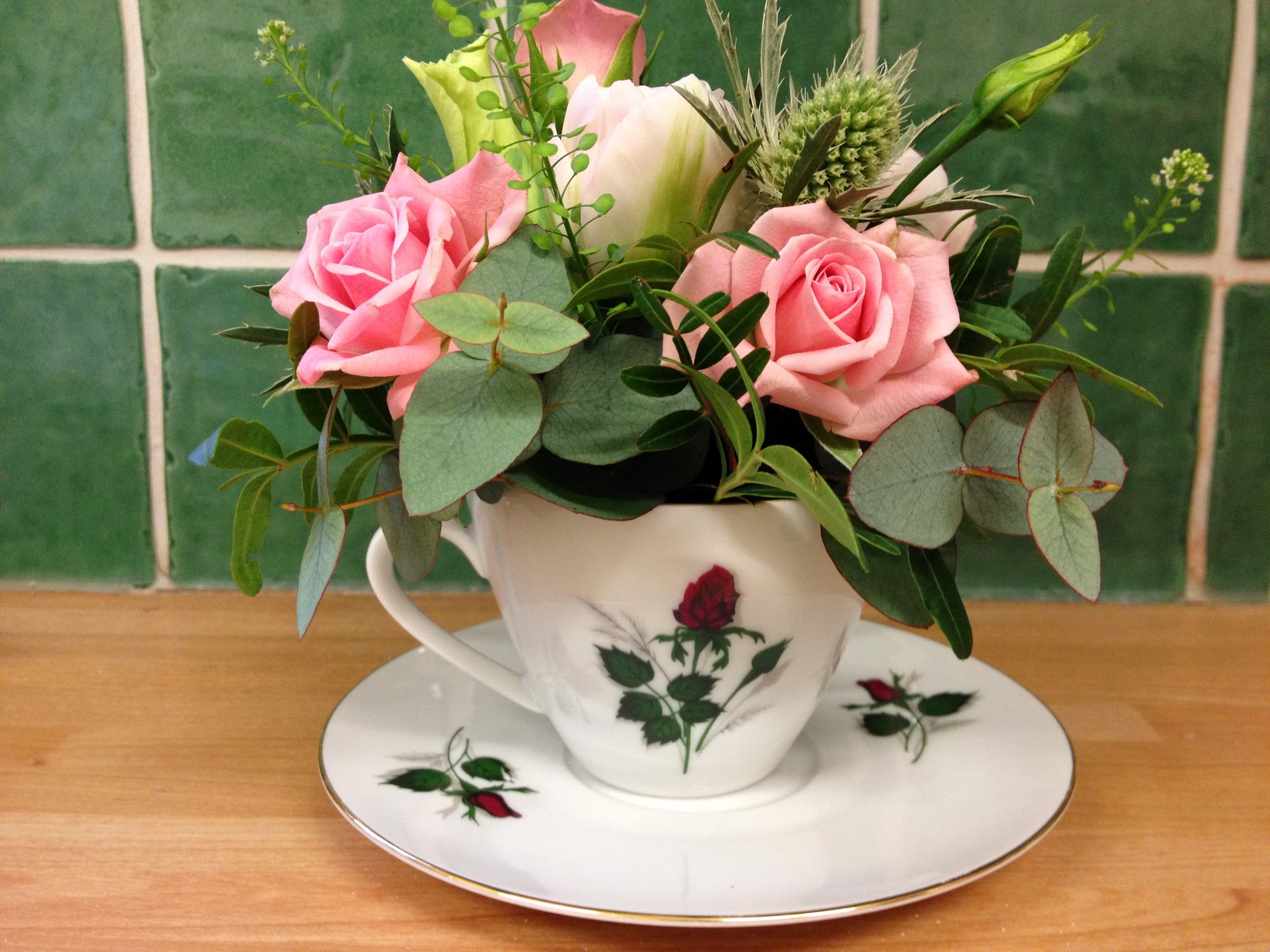 Pink roses and eucalyptus in a teacup on a saucer HD Wallpaper