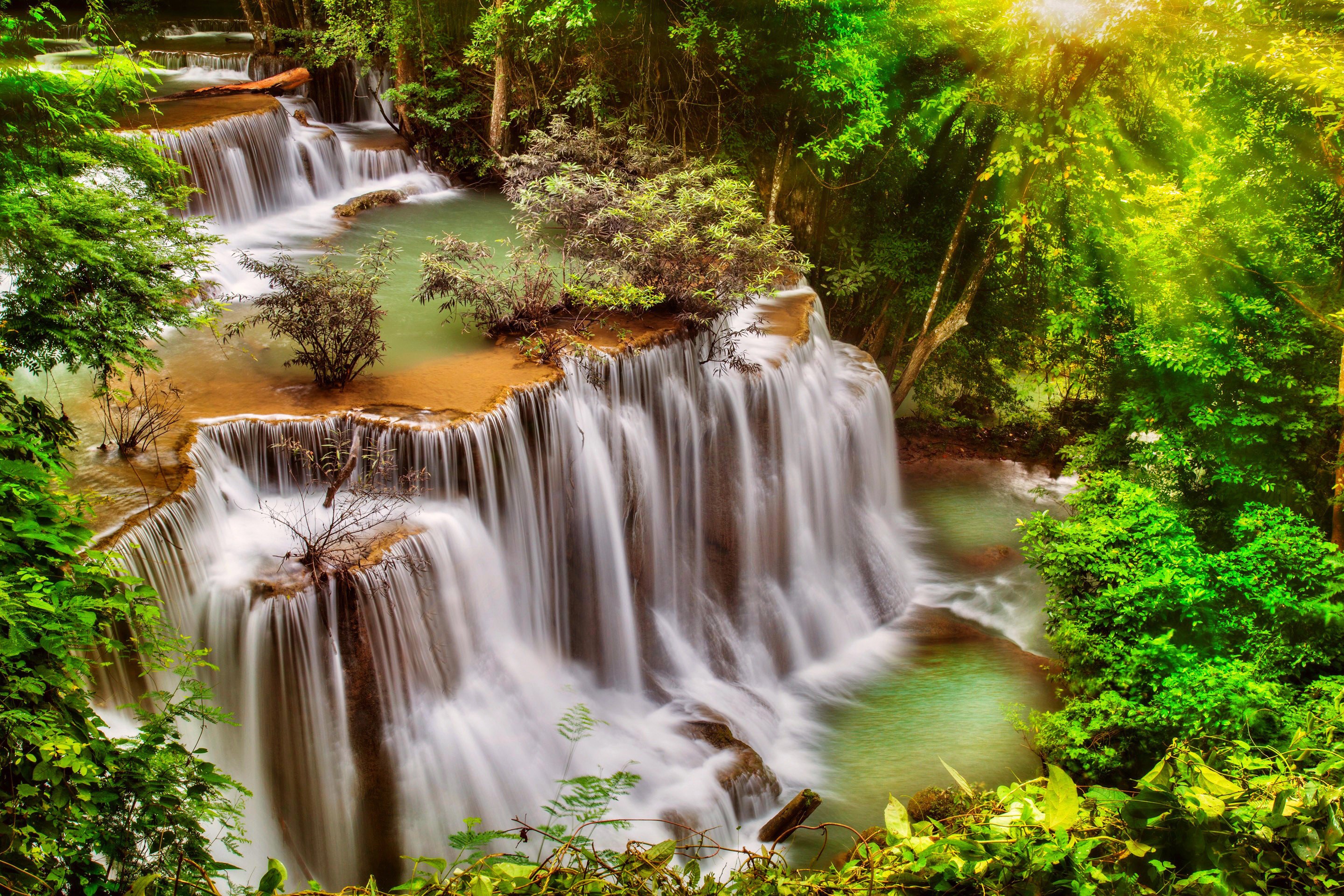 Tiered waterfalls in a lush green forest in Thailand HD Wallpaper