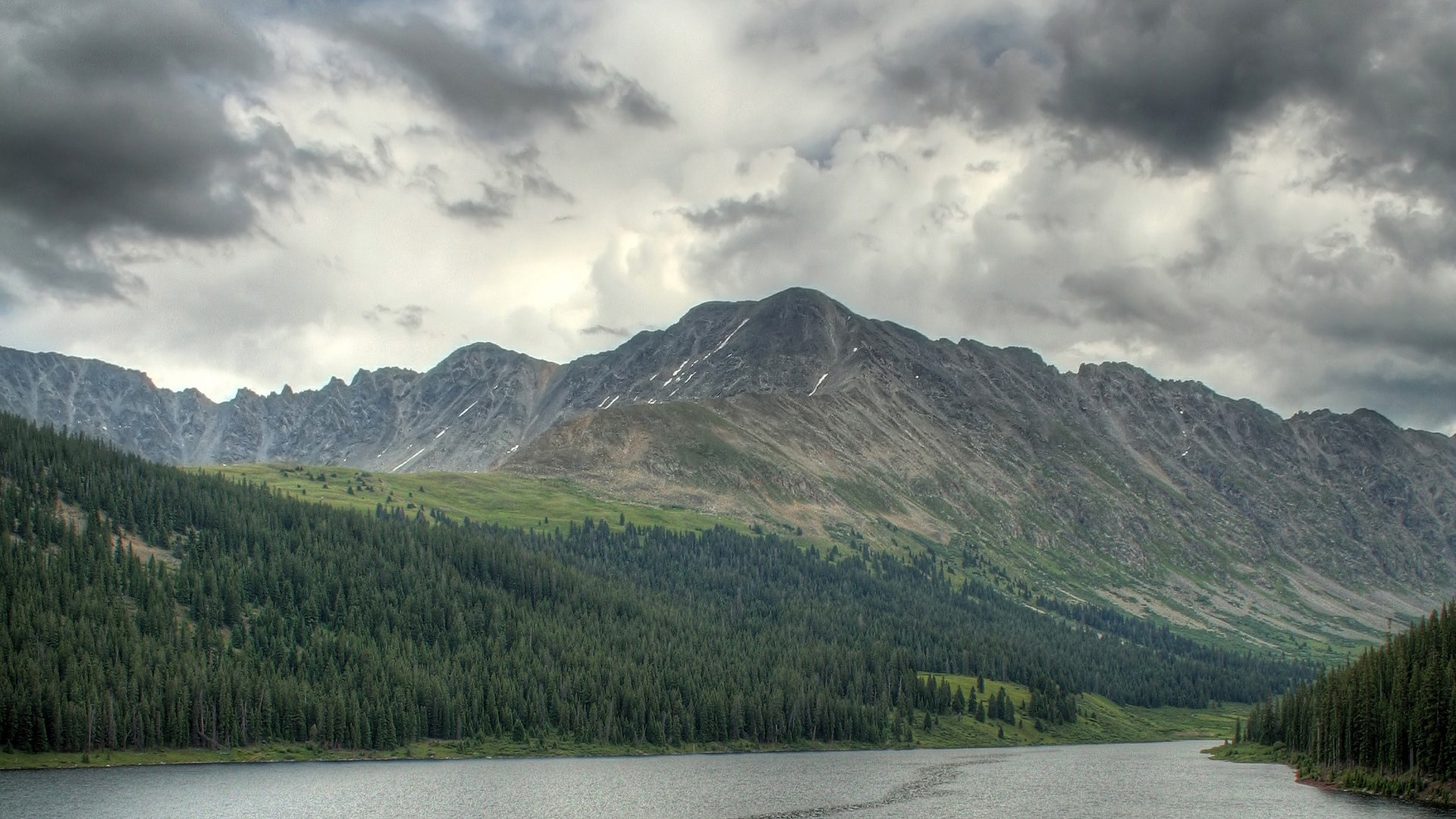 Lake and mountains with pine forest under cloudy sky HD Wallpaper