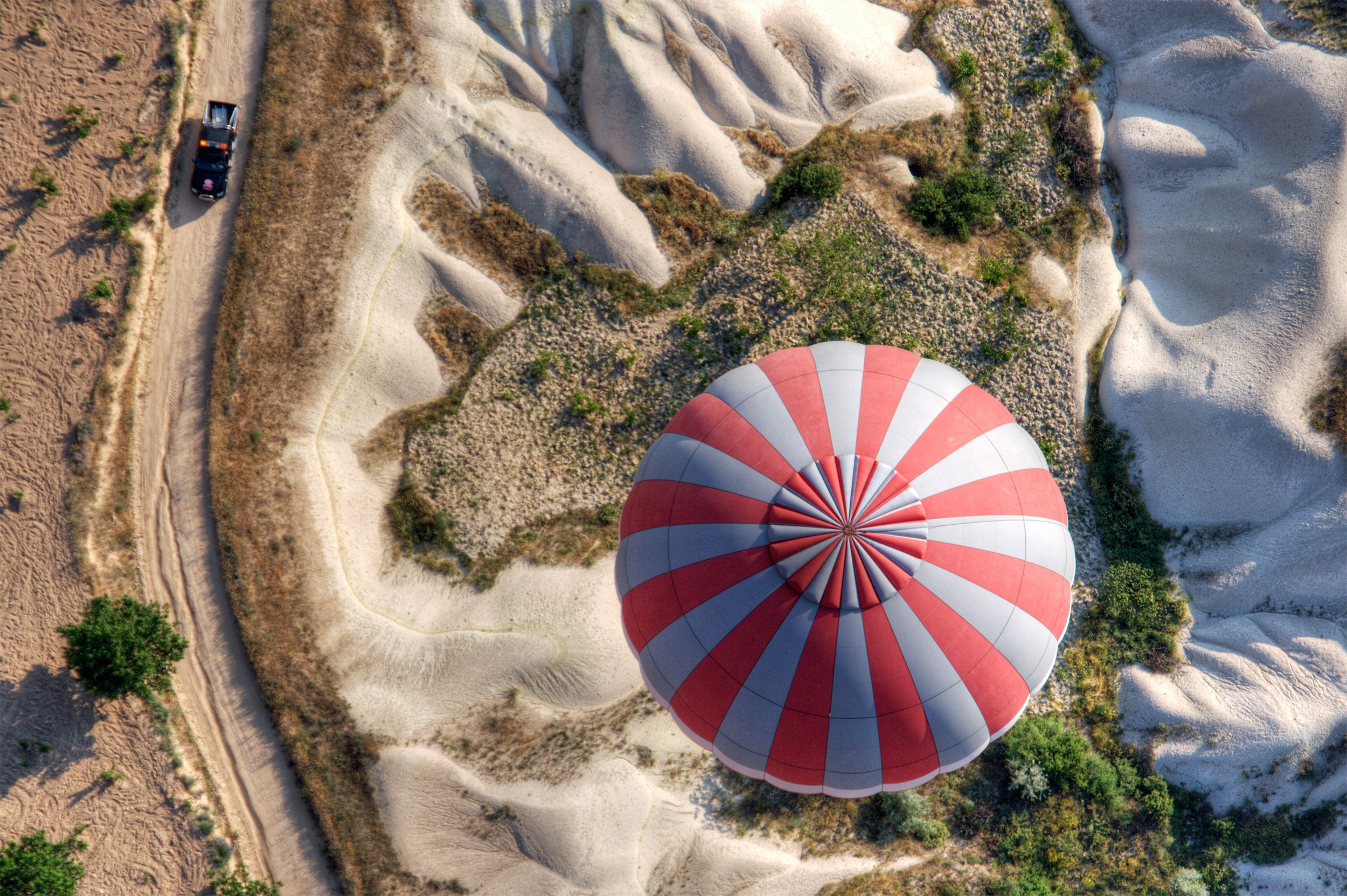 Hot air balloon over Cappadocia landscape with vehicle HD Wallpaper