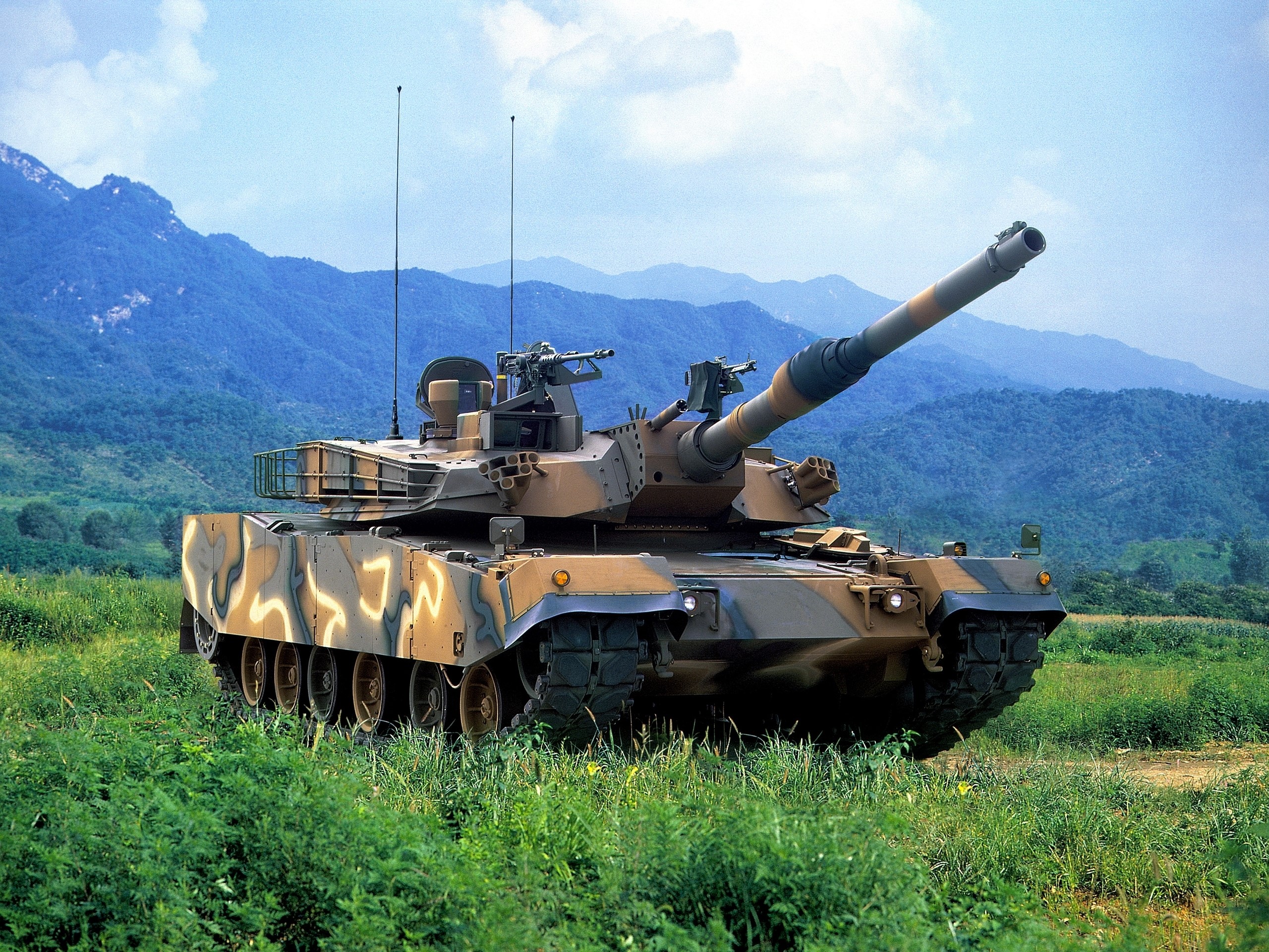 K1A1 tank in a grassy field with mountains HD Wallpaper
