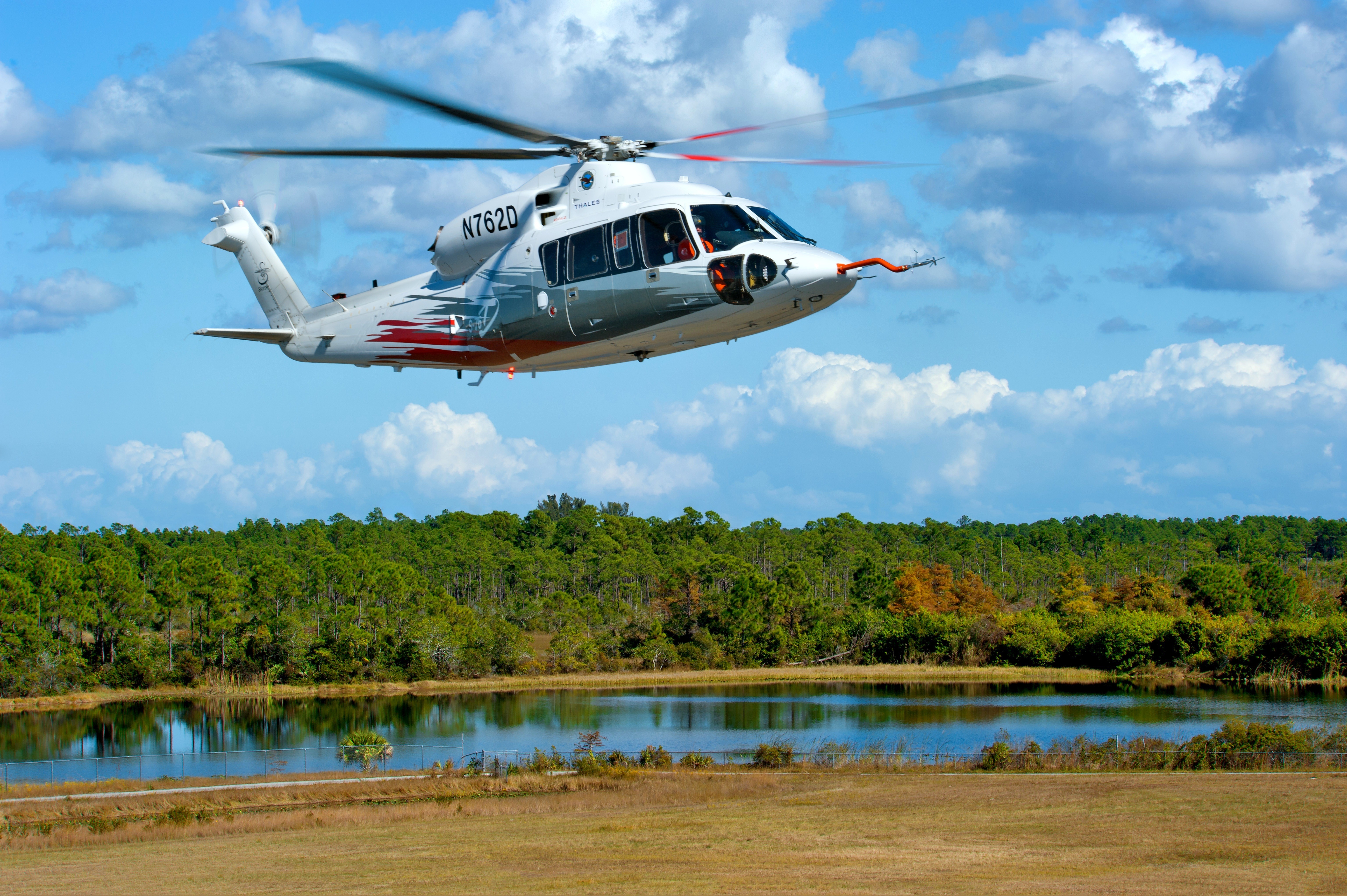 S-76D Helicopter flying over a lake and forest HD Wallpaper
