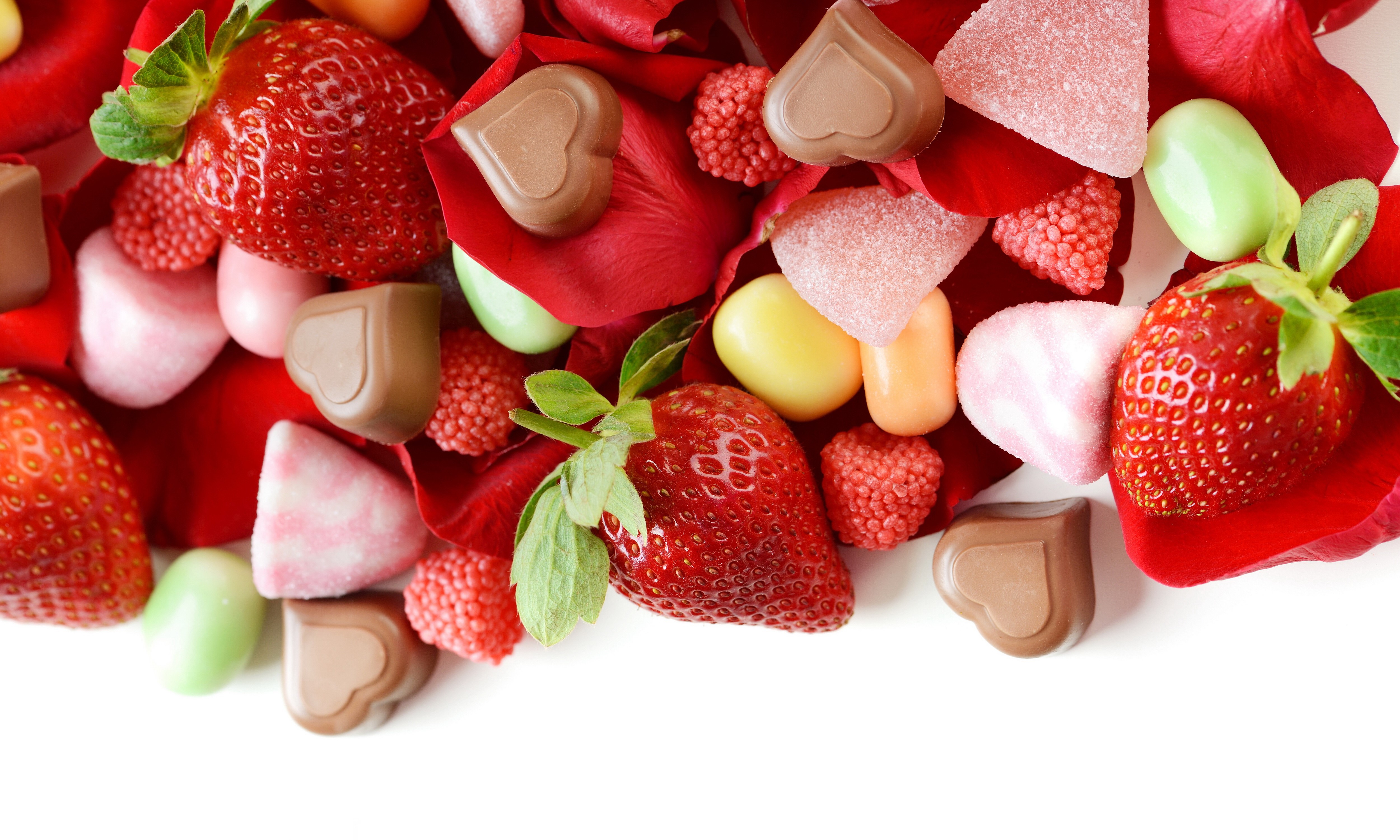 Strawberries and assorted candies on rose petals HD Wallpaper