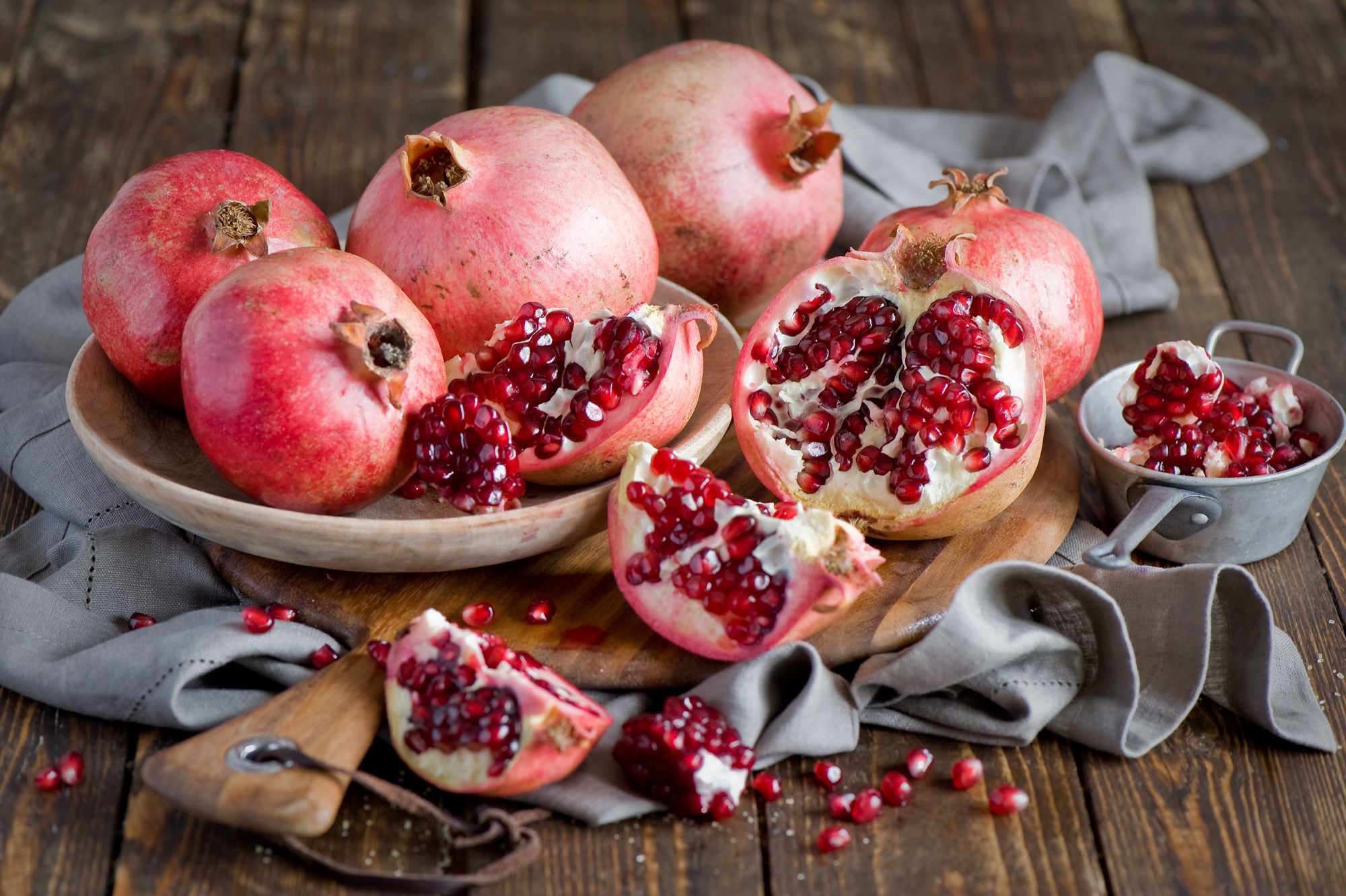 Pomegranates on a wooden table with a grey cloth HD Wallpaper