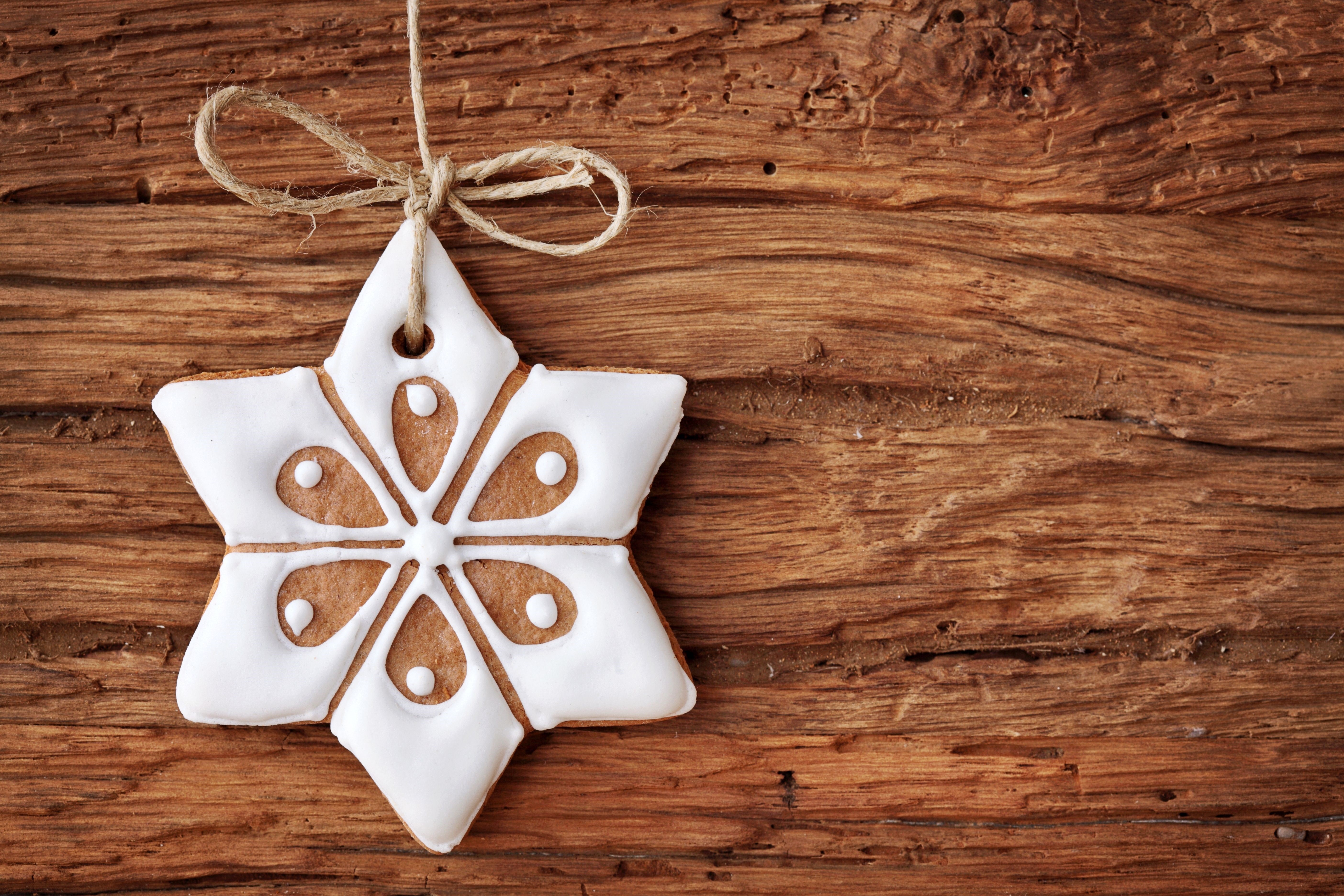 Star-shaped gingerbread cookie with white icing on wood HD Wallpaper