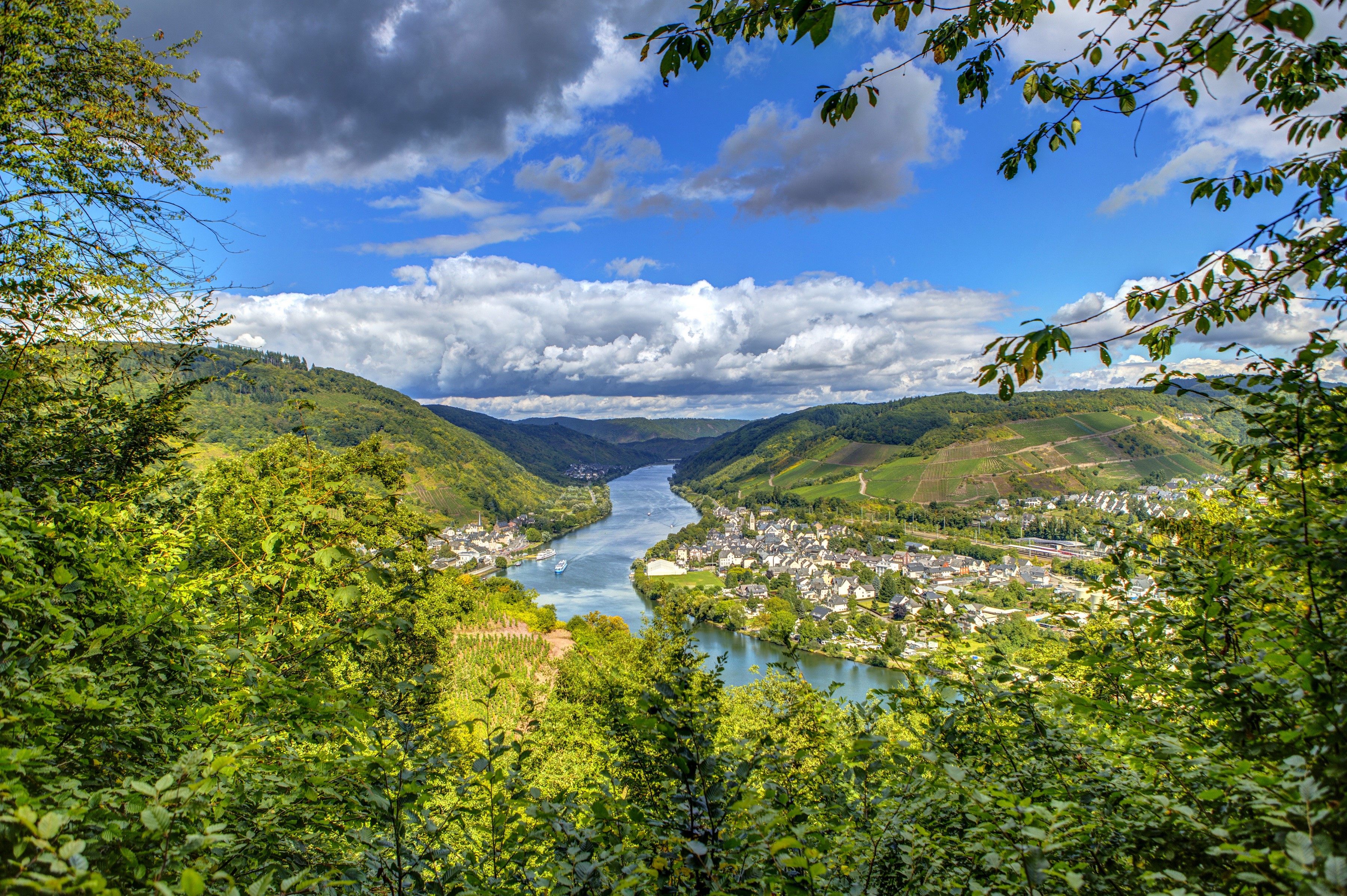 River valley with town and vineyards under cloudy sky HD Wallpaper
