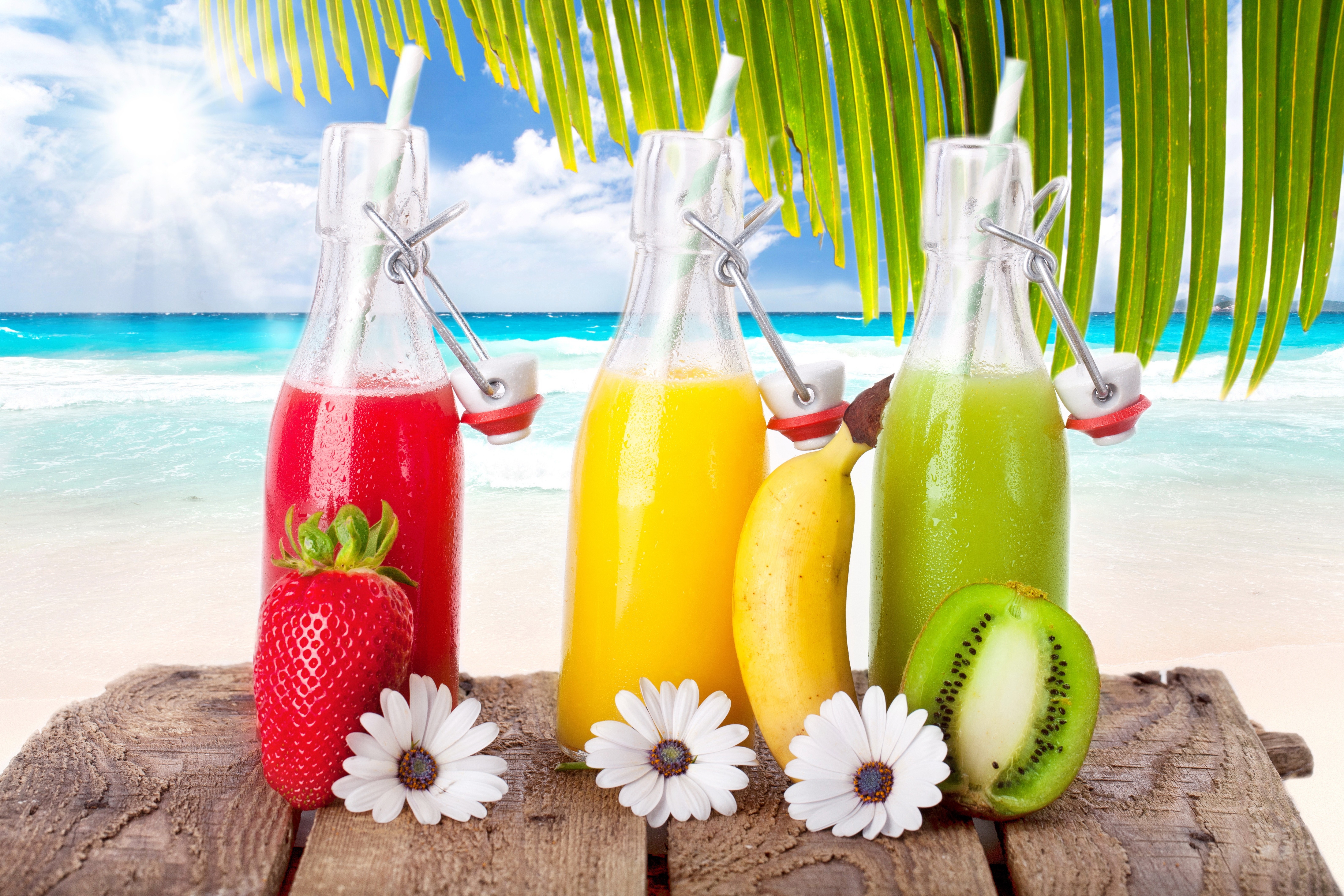 Strawberry, Banana, and Kiwi Juice Bottles on a Beach HD Wallpaper