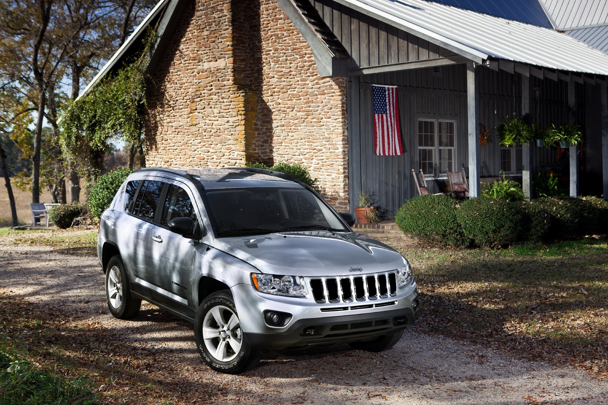 Silver Jeep Compass parked in front of a stone and wood house with American flag HD Wallpaper