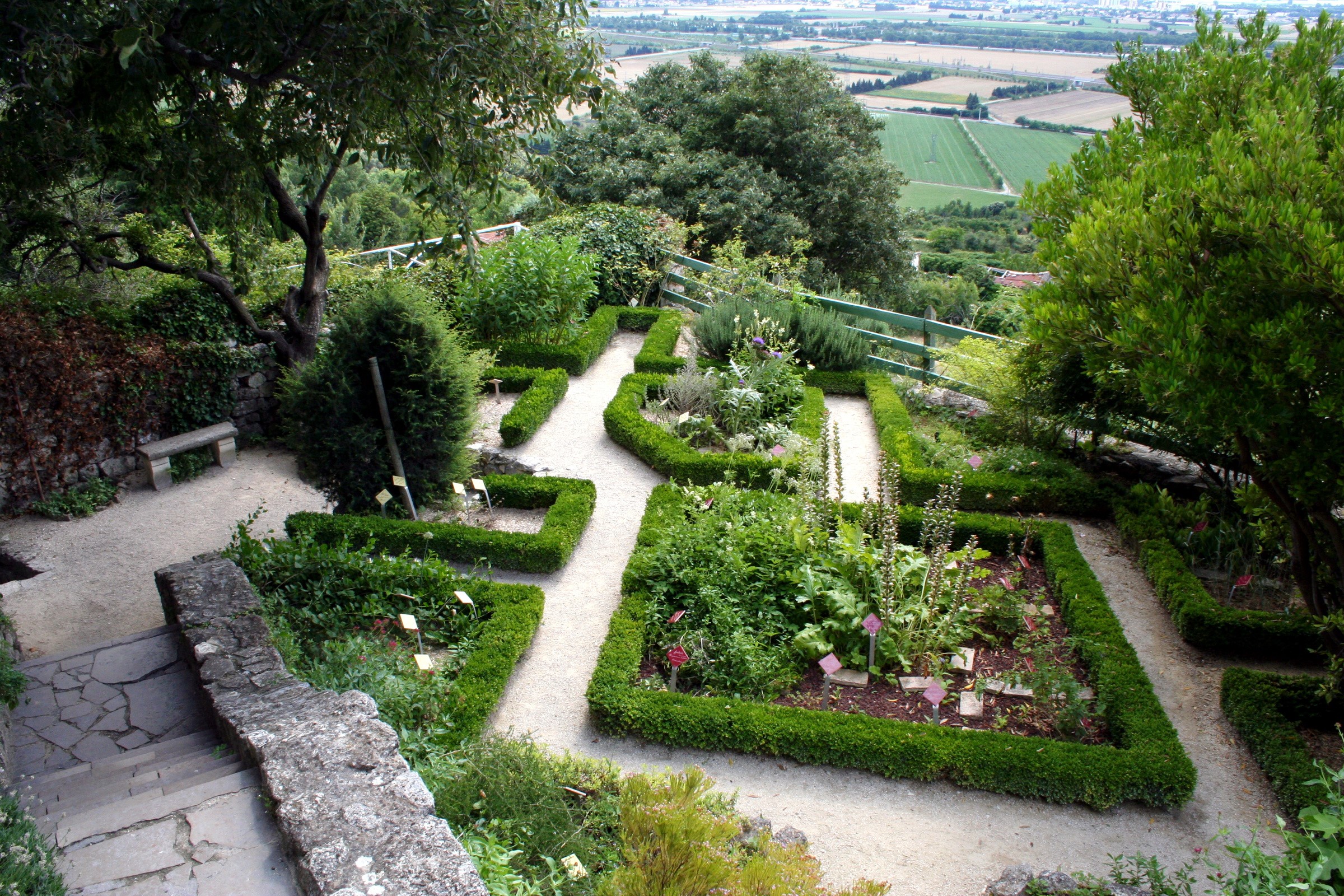 Formal garden with manicured shrubs and distant landscape in Goudargues, France HD Wallpaper