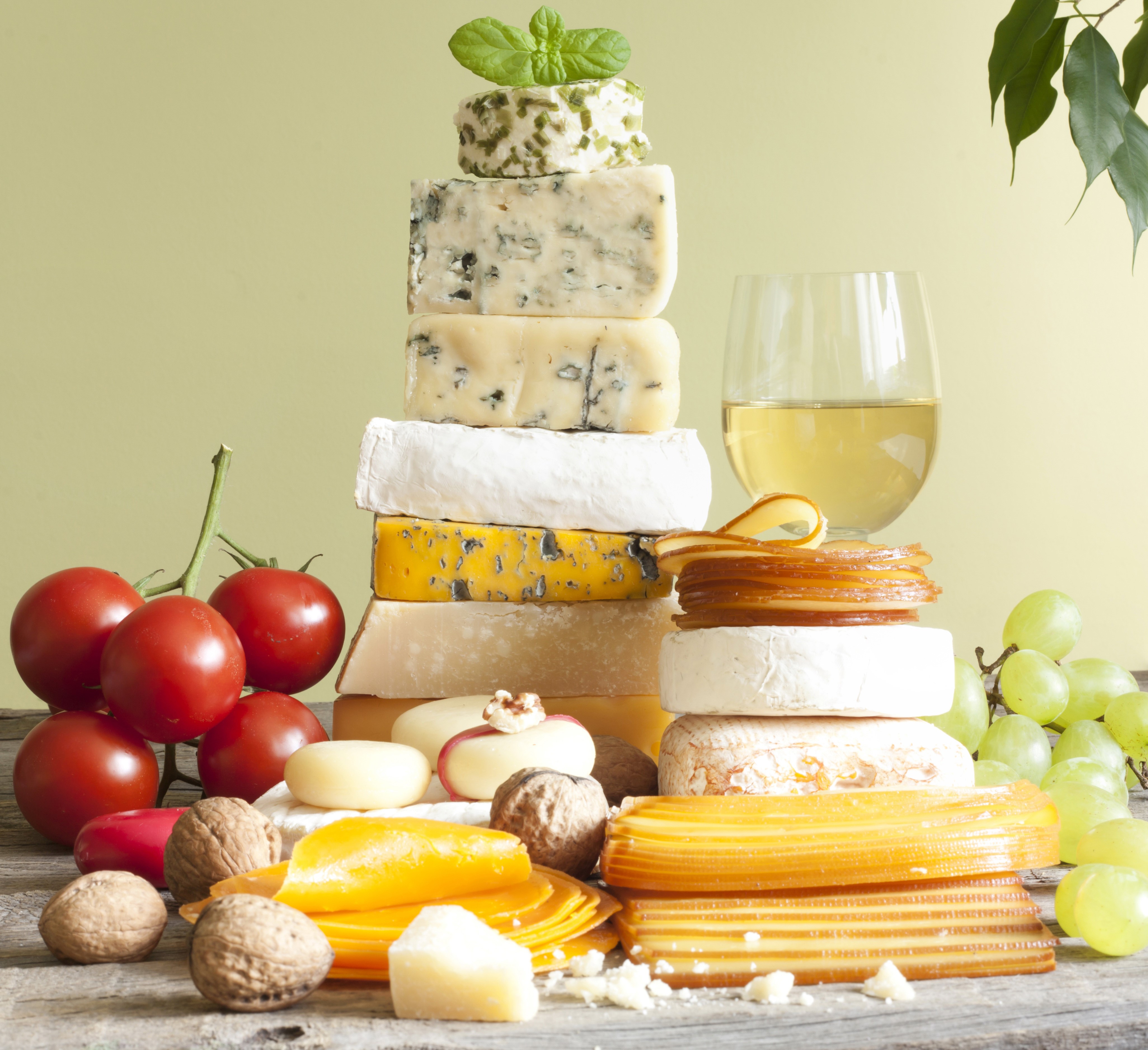 Cheese platter with tomatoes, nuts, grapes, and white wine HD Wallpaper