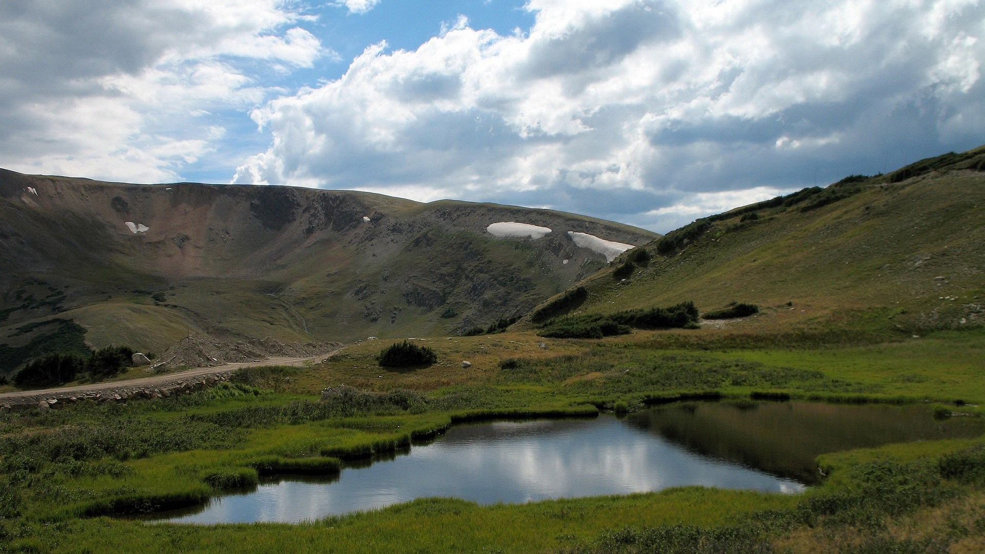 Mountain landscape with a small pond and cloudy sky HD Wallpaper