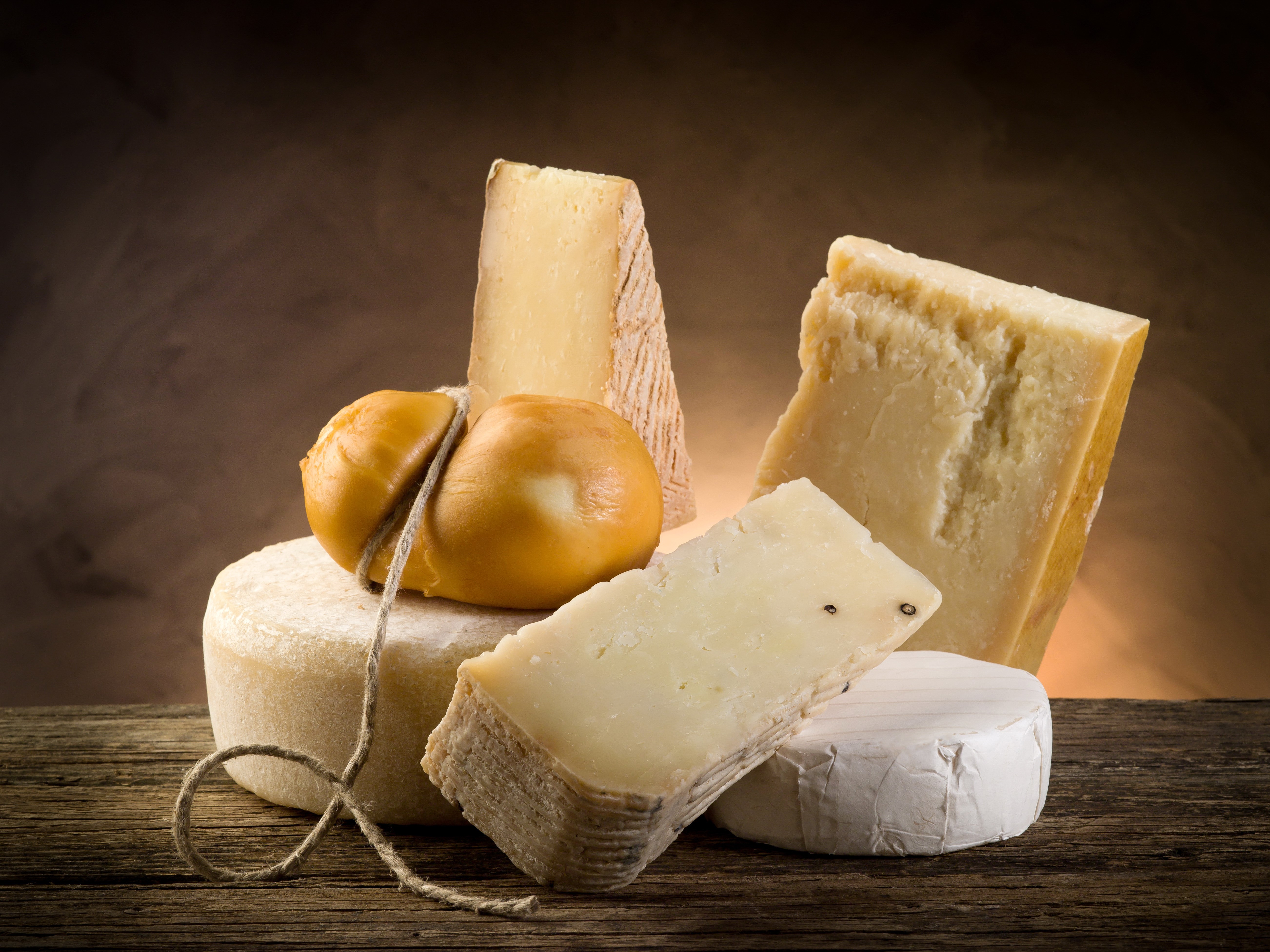 Assortment of cheeses on a wooden table HD Wallpaper