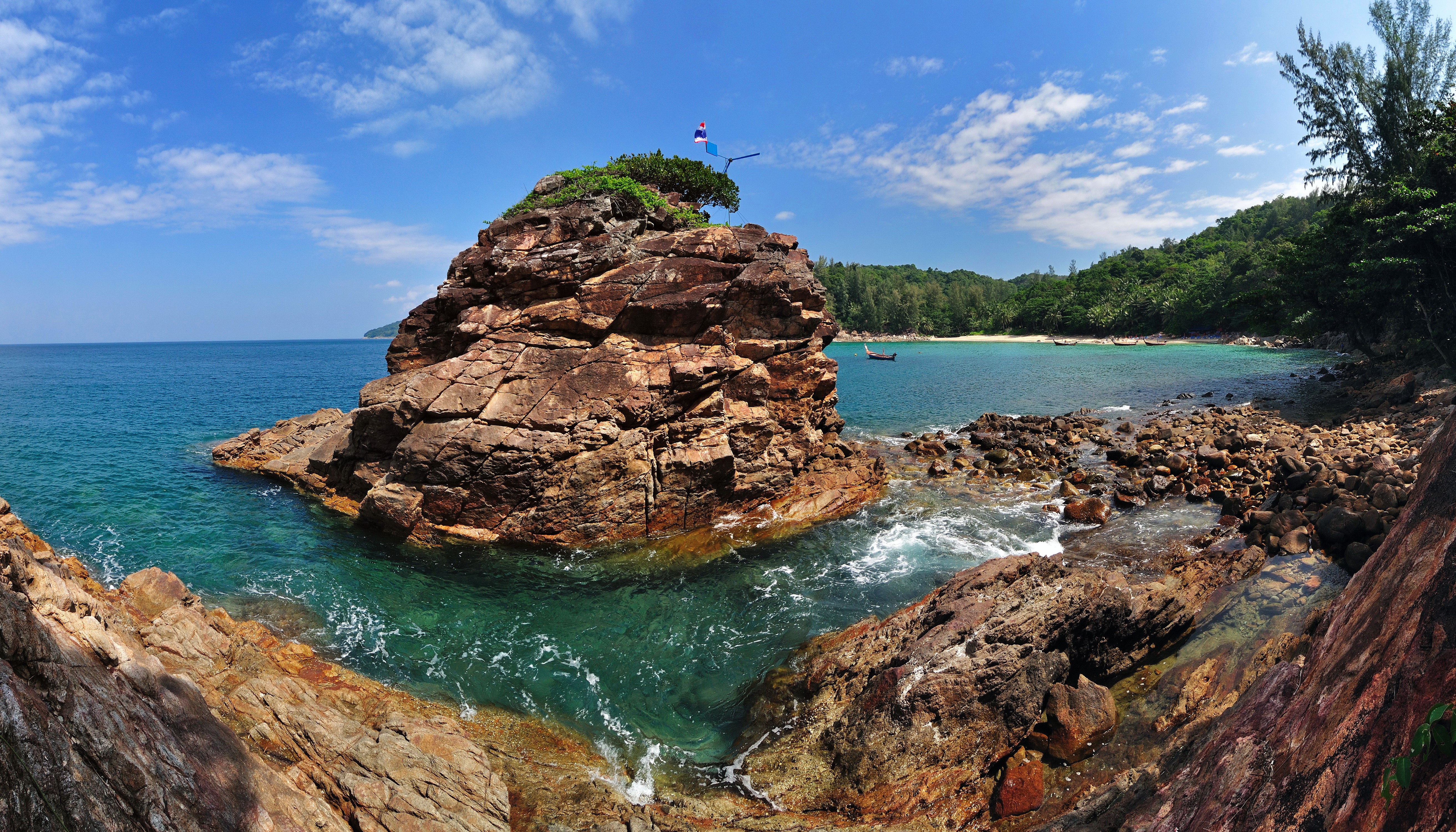 Rocky island with trees and flags in the sea HD Wallpaper