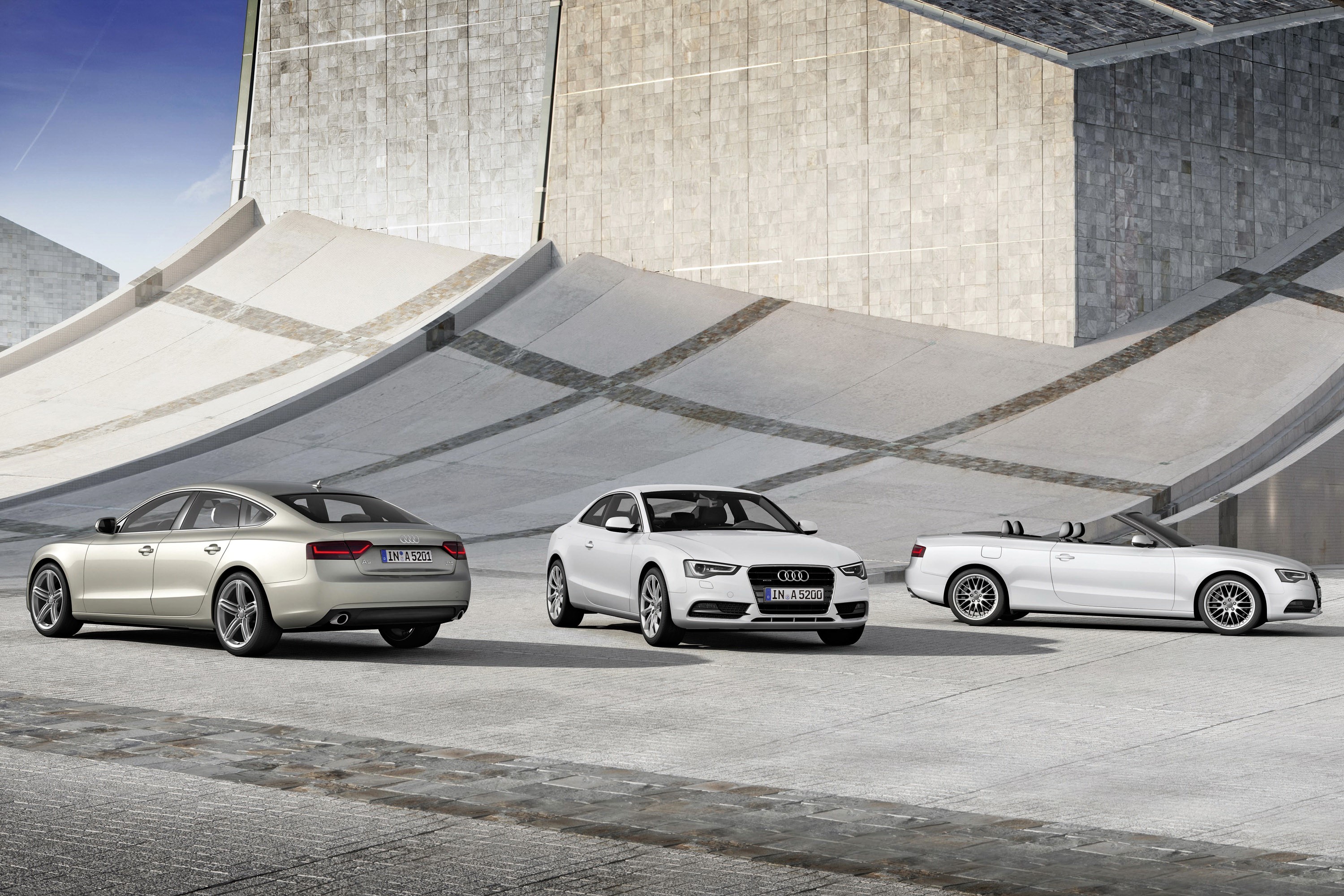 Three Audi A5 models in front of a modern building HD Wallpaper