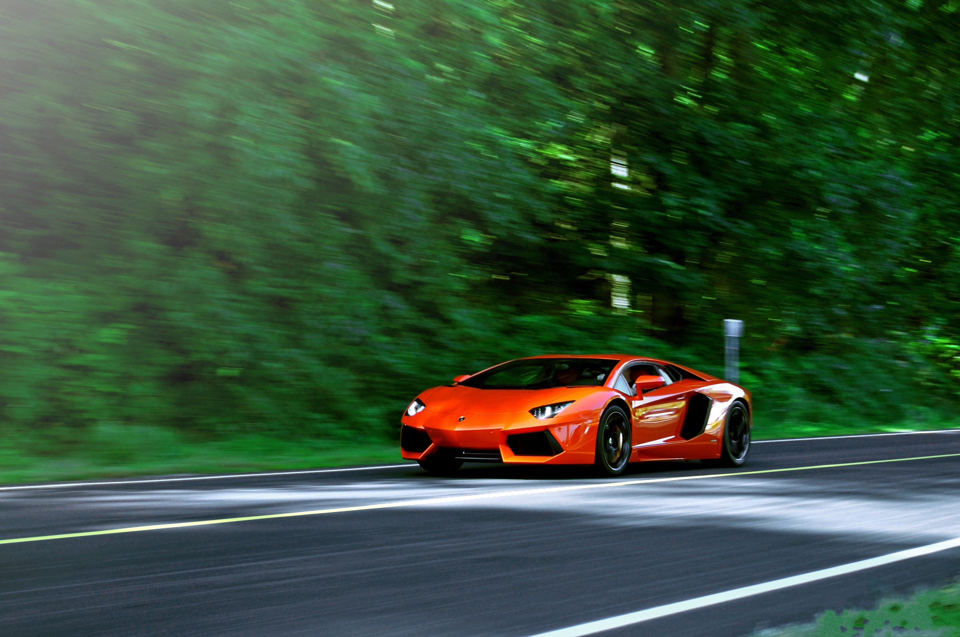 Orange Lamborghini Aventador LP700-4 driving on a road HD Wallpaper