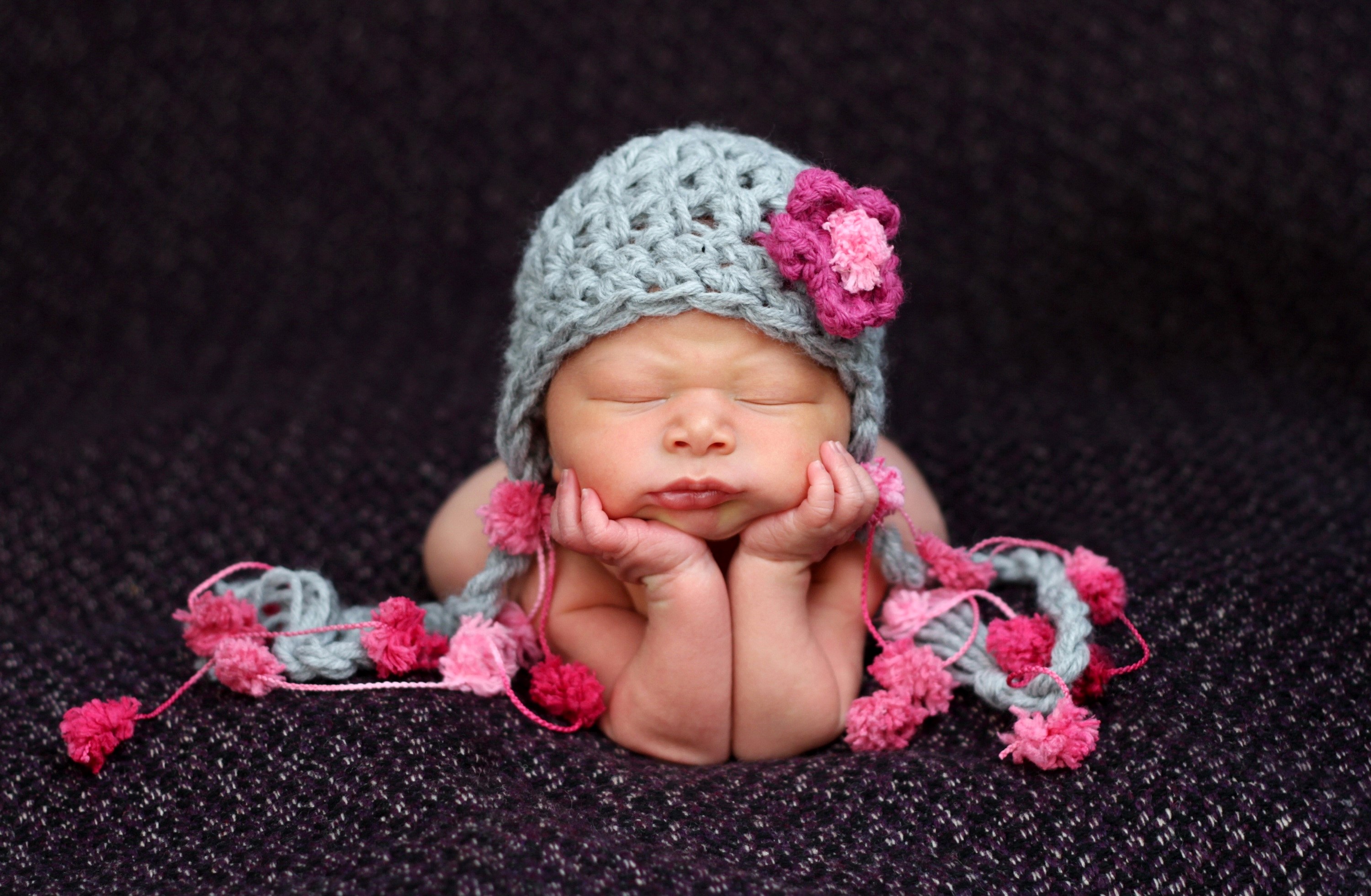 Newborn baby wearing a knitted hat with flowers HD Wallpaper