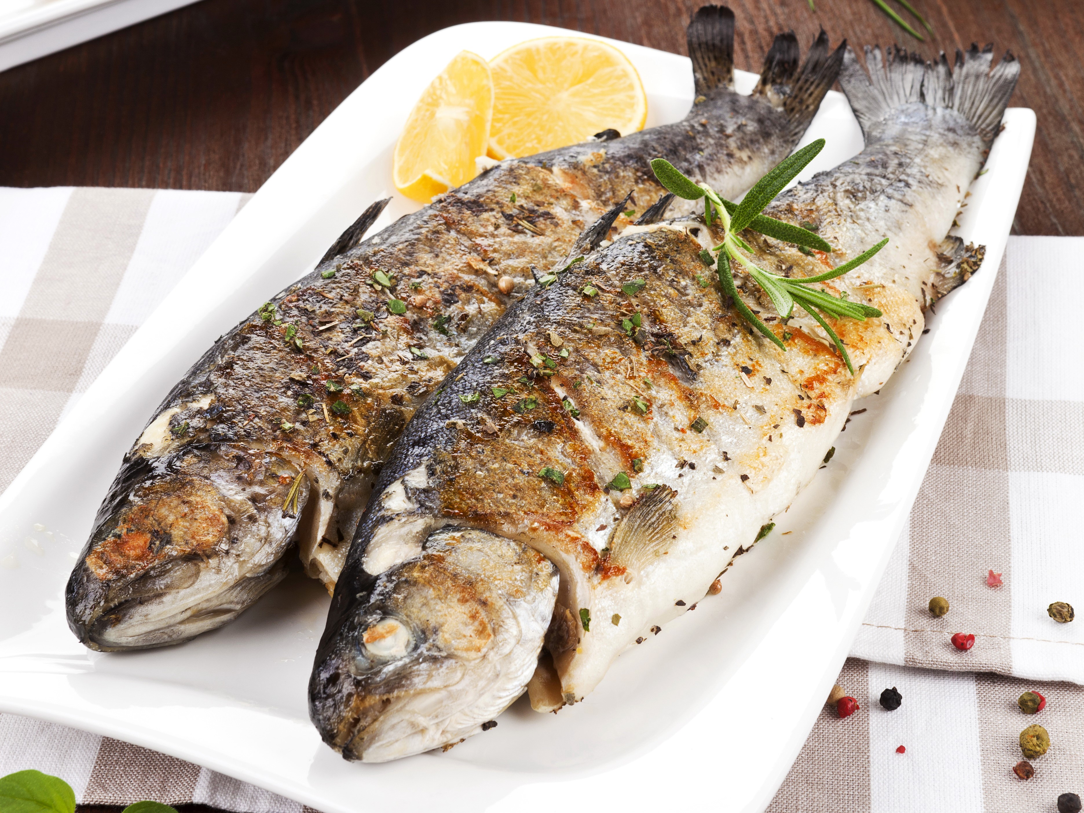 Two grilled fish with lemon and rosemary on a platter HD Wallpaper
