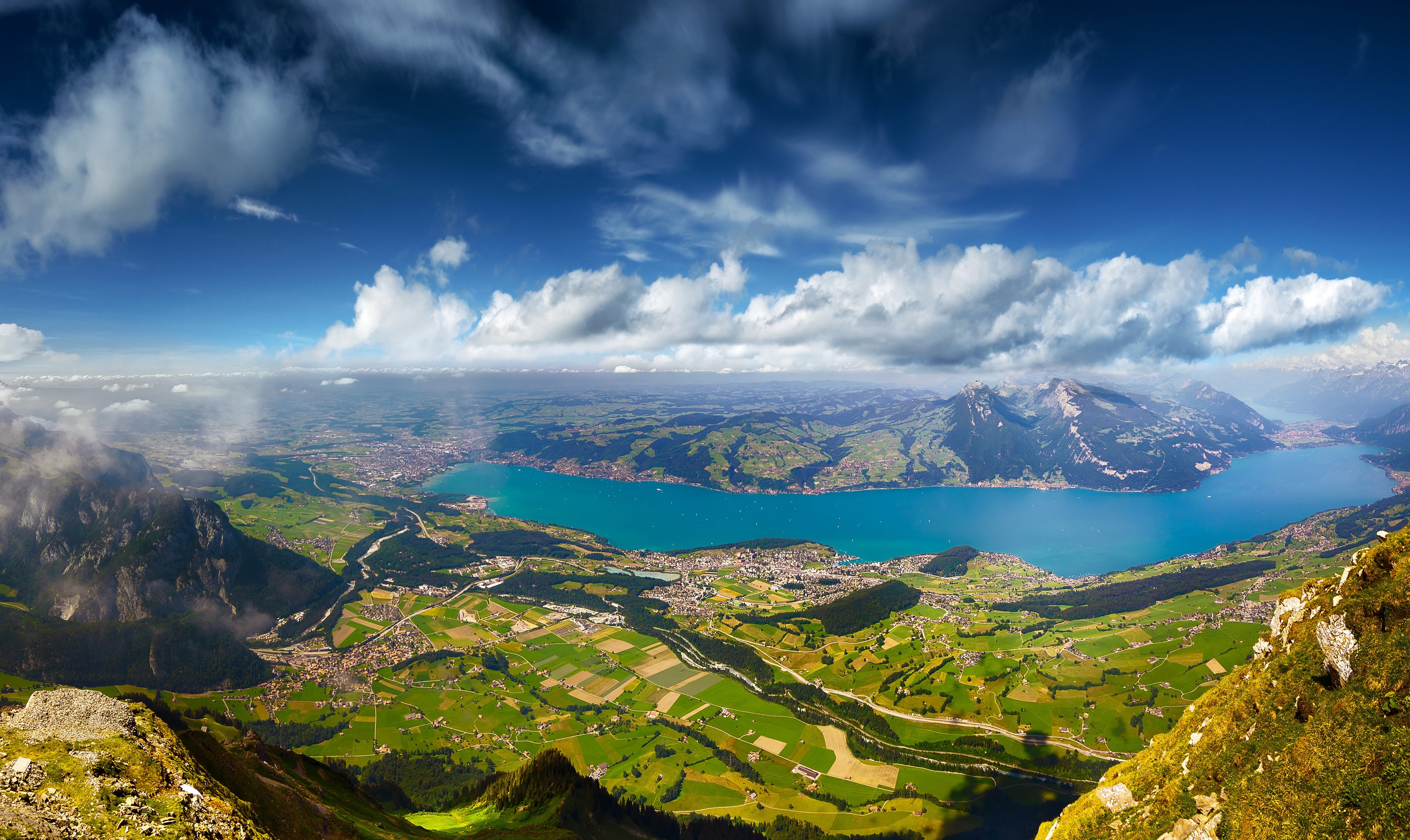 Panoramic view of a lake and mountains under a cloudy sky HD Wallpaper