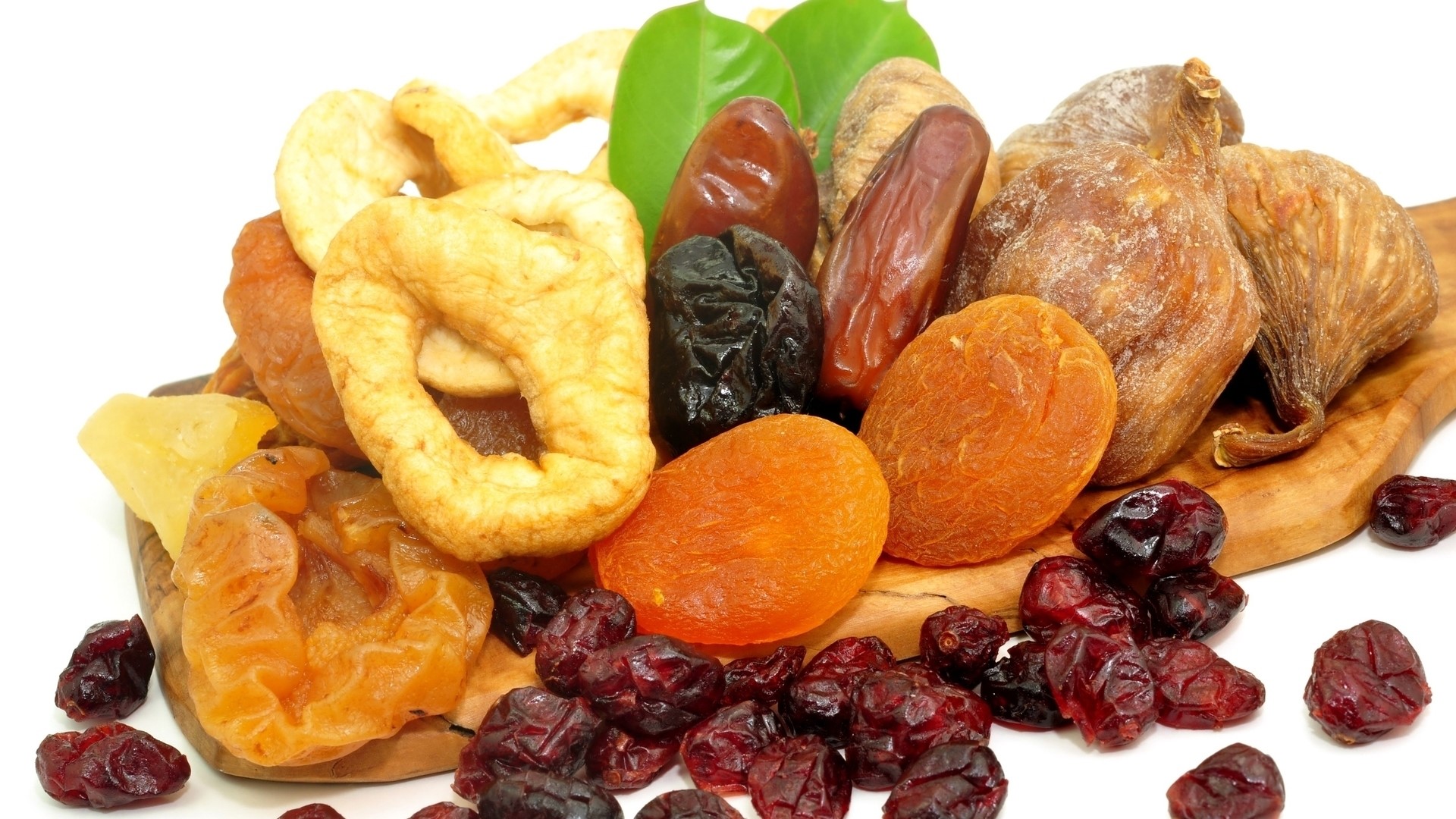 A pile of assorted dried fruits on a wooden board HD Wallpaper