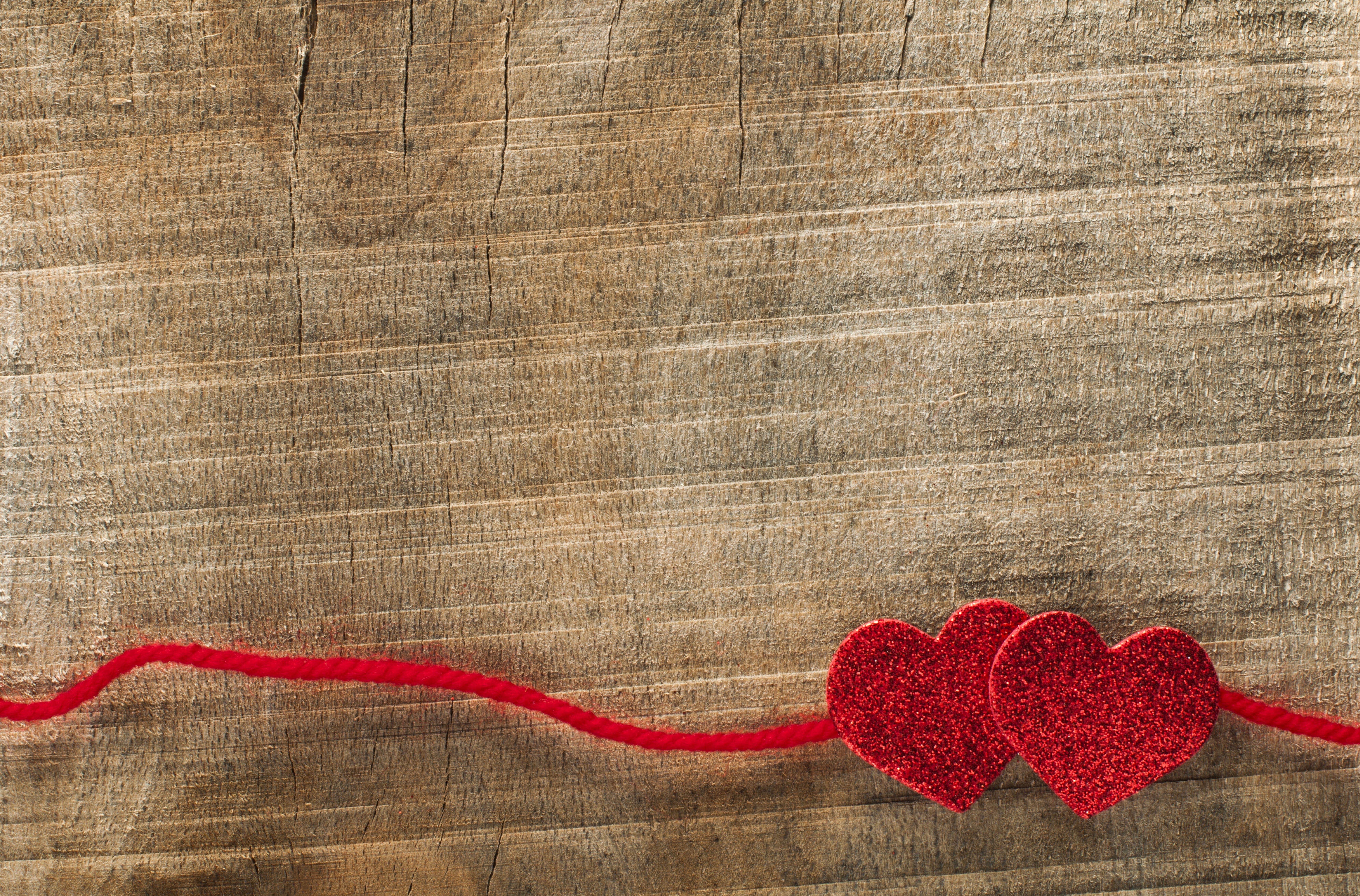 Two red glitter hearts on a red string on wood HD Wallpaper