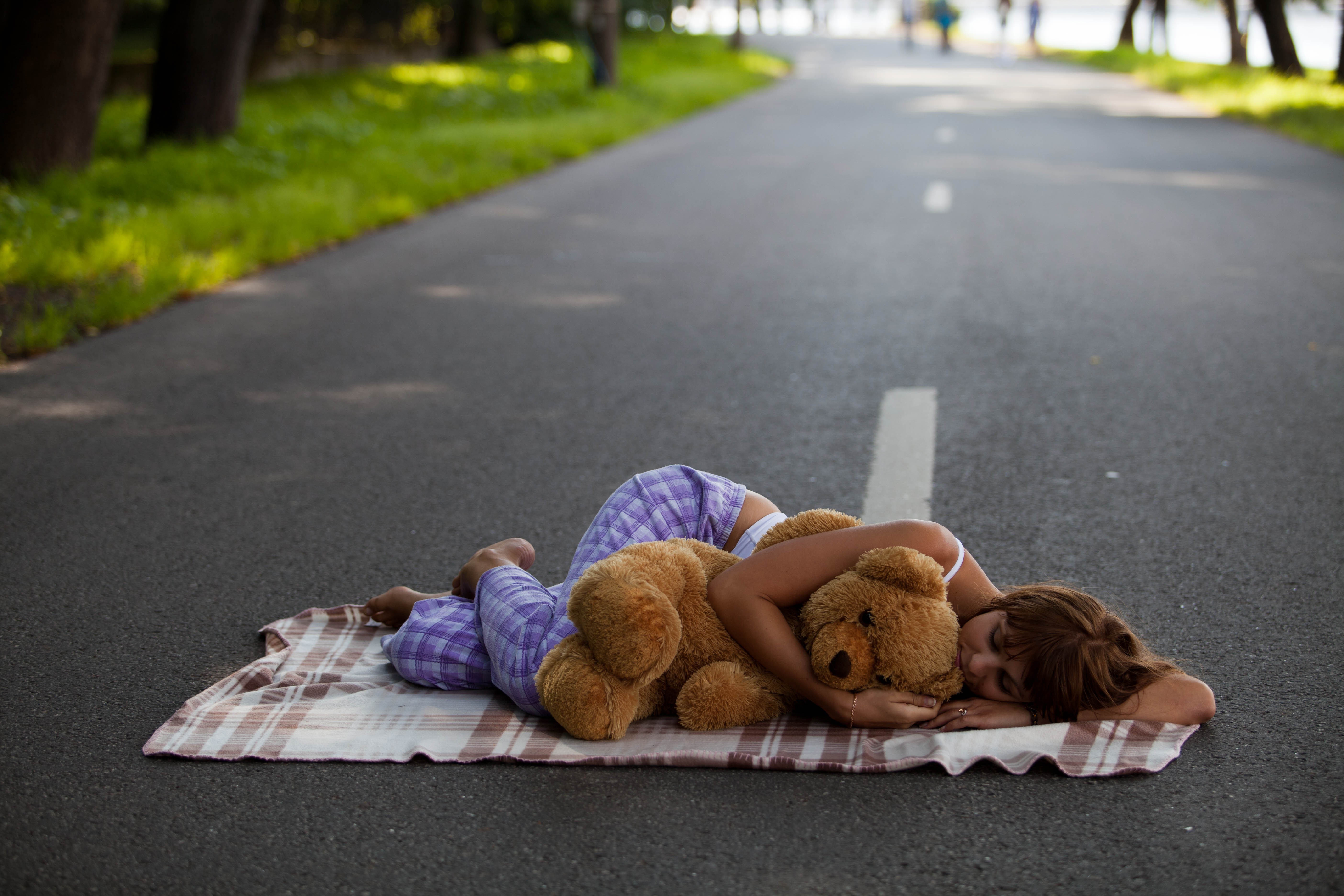 Girl sleeping with teddy bear on road HD Wallpaper