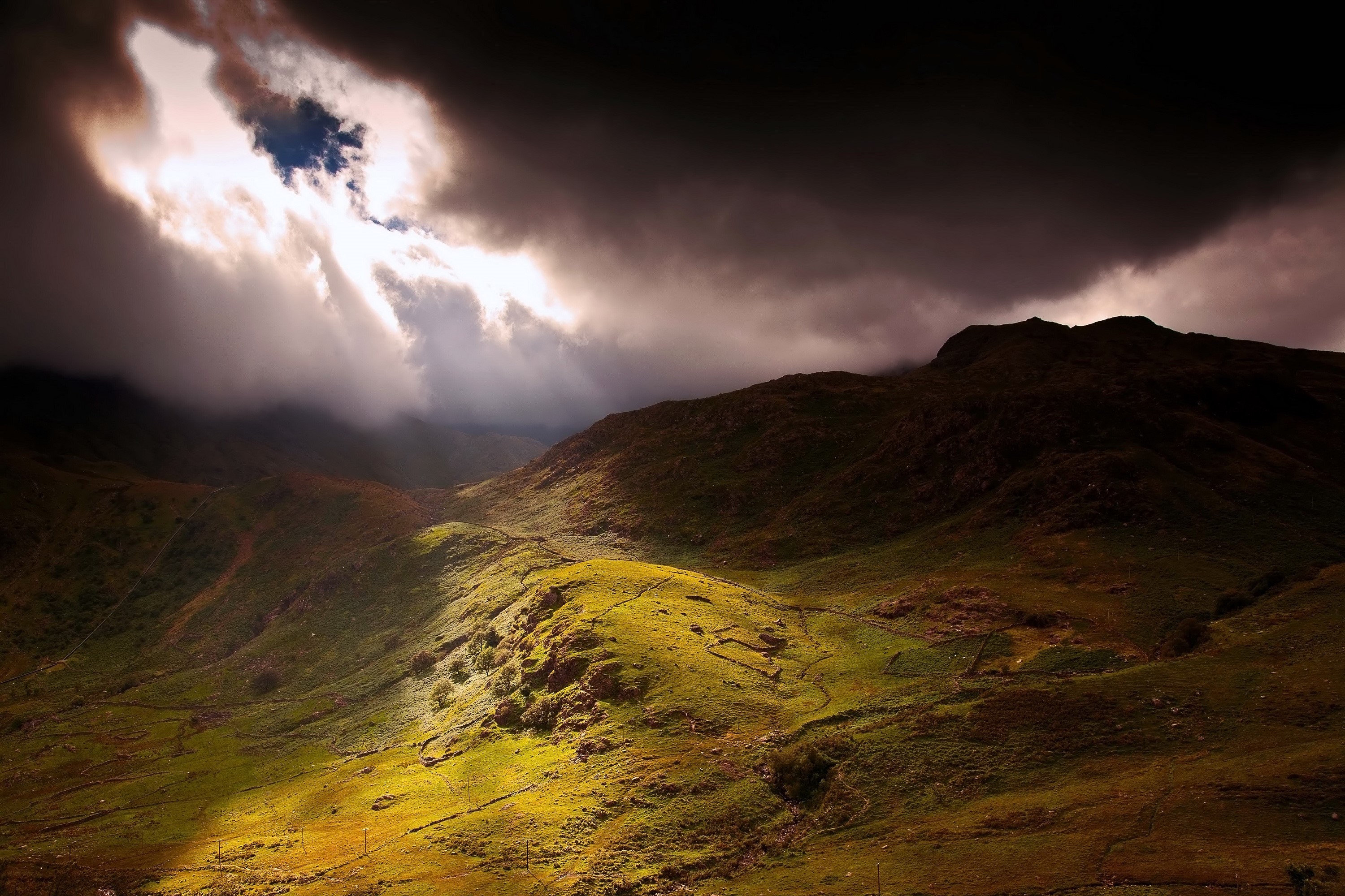 Sunlight breaking through clouds over mountains in Snowdonia HD Wallpaper