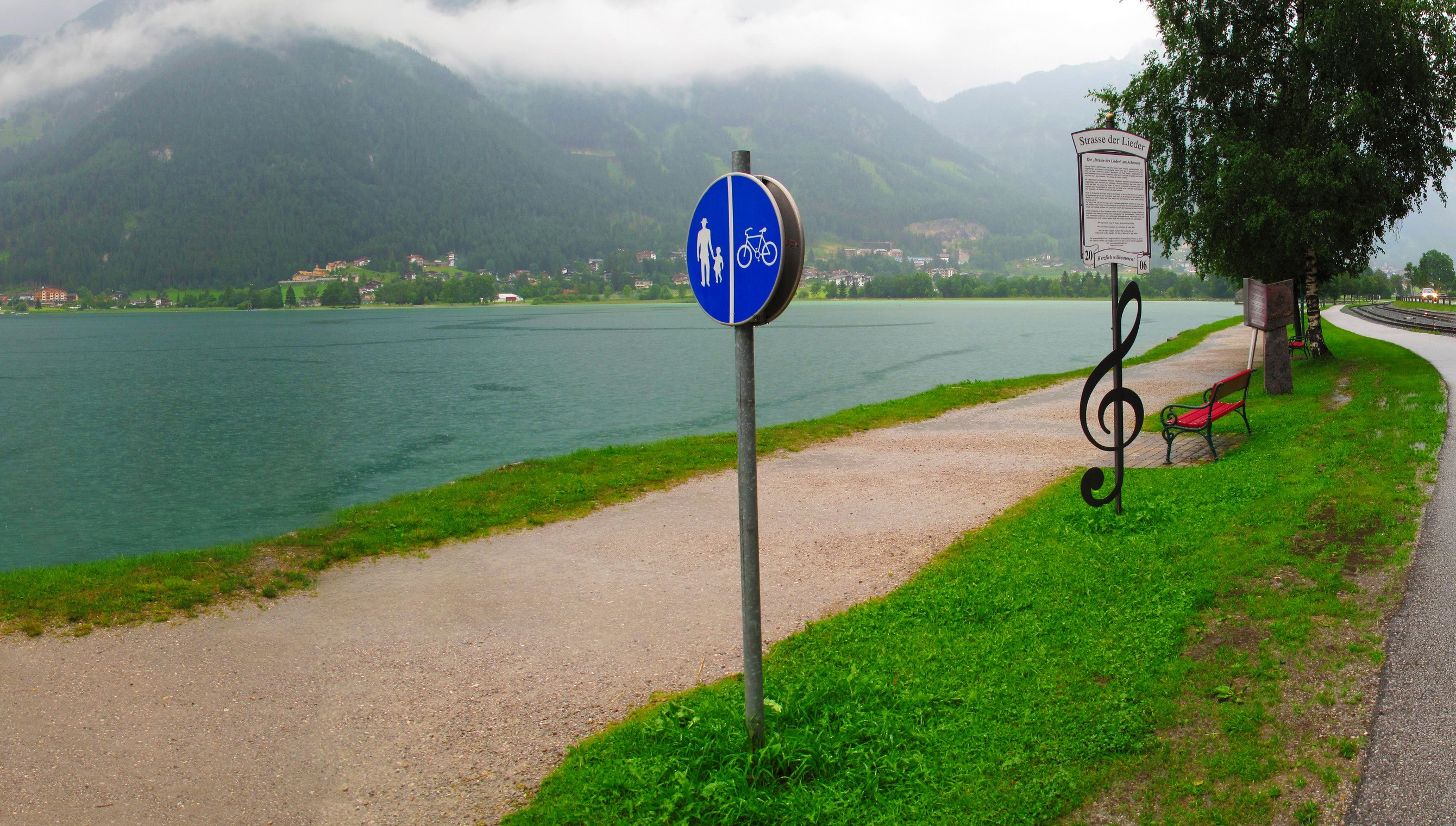 Path by a lake with mountains and a signpost HD Wallpaper