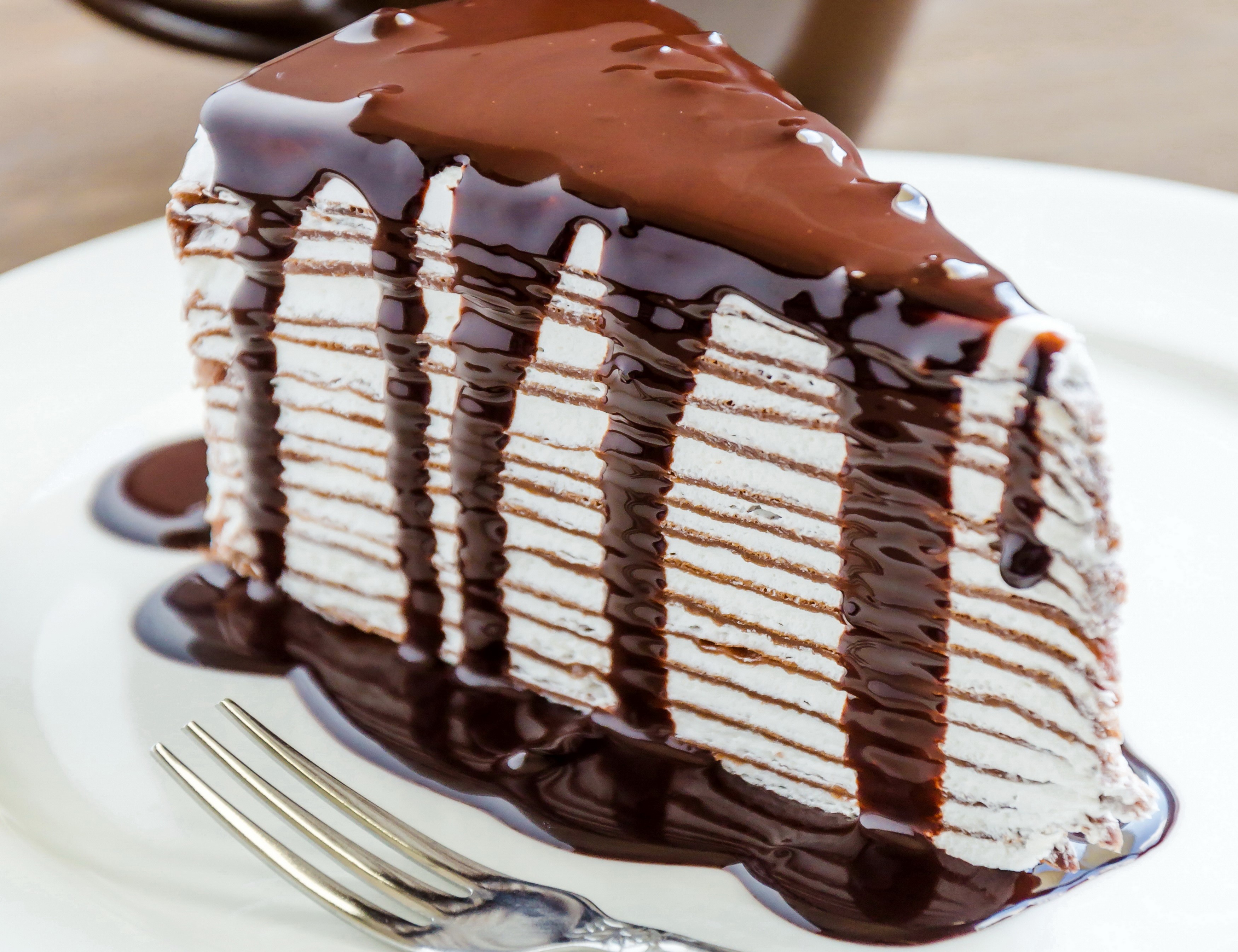 Slice of chocolate crepe cake with chocolate sauce HD Wallpaper