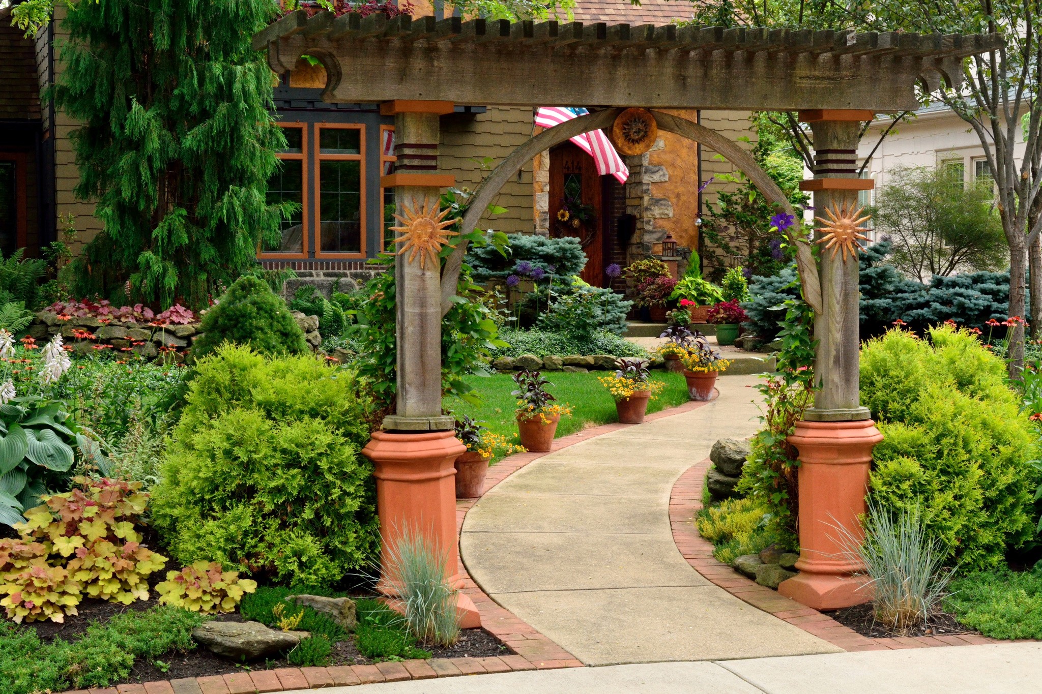 Garden path through an archway with shrubs and flowers HD Wallpaper
