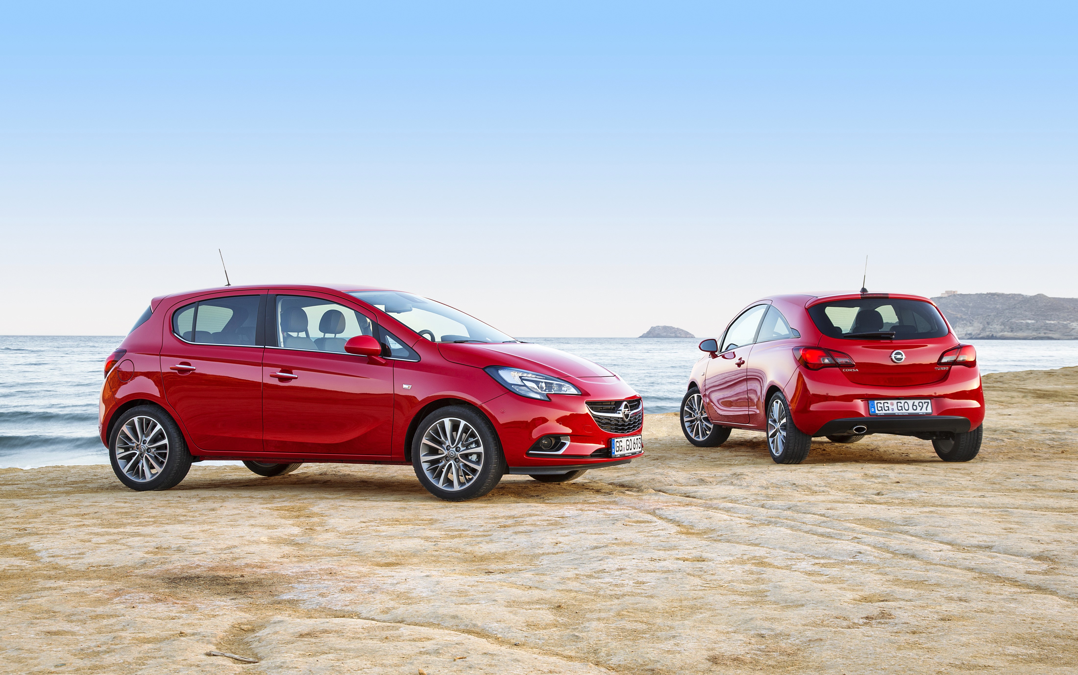 Two red Opel Corsa cars on a beach HD Wallpaper