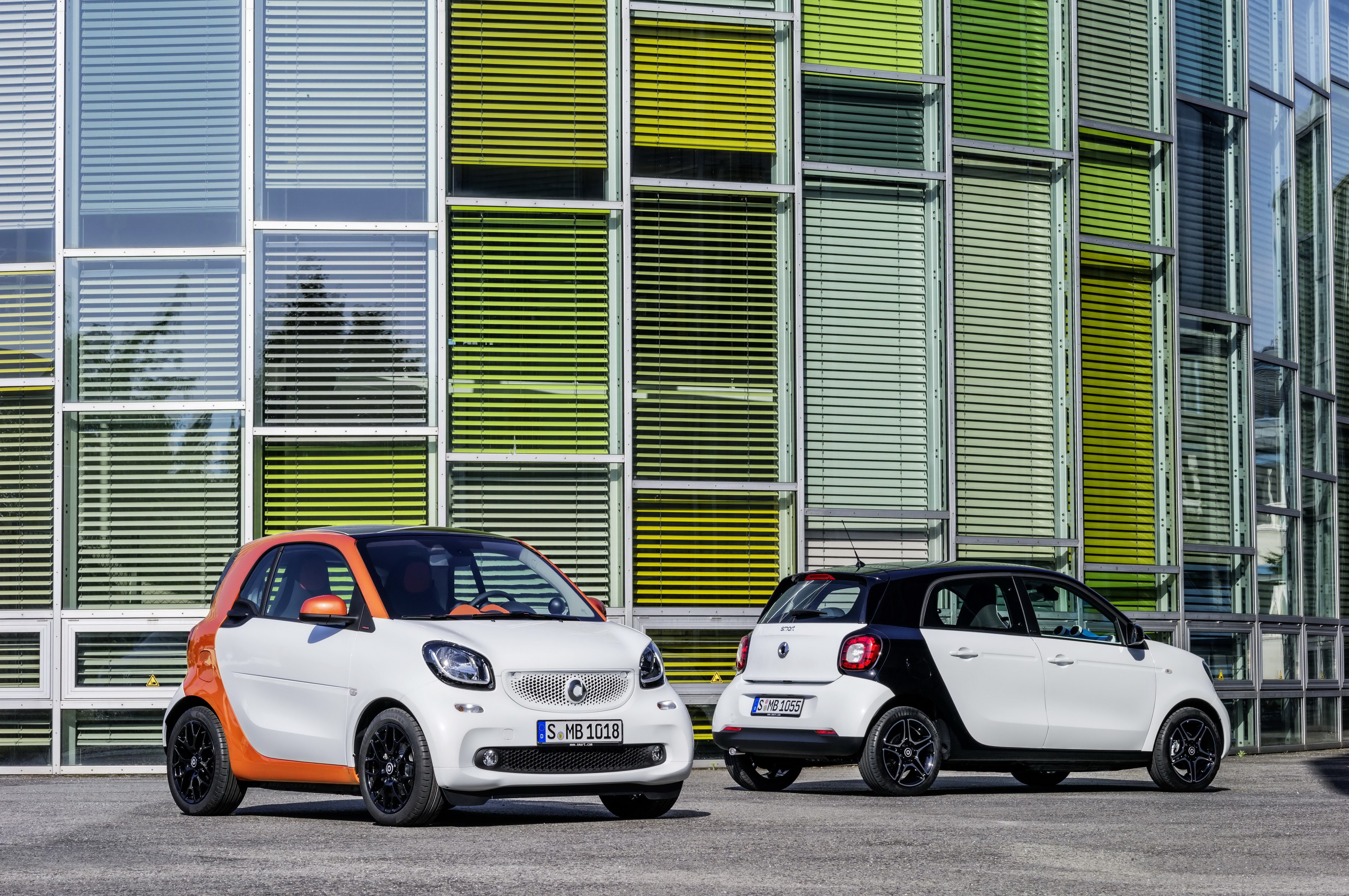 Two Smart ForFour cars in front of a modern building HD Wallpaper