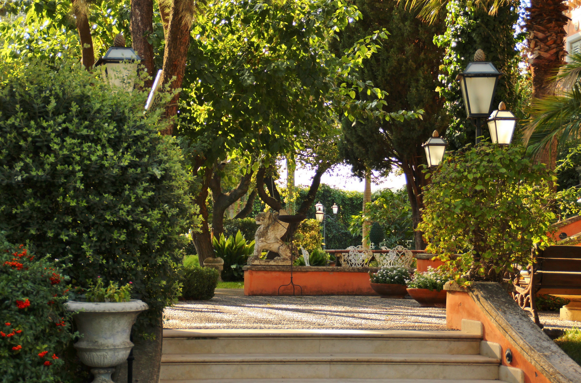 Garden with stone lion statue and street lamps in Italy HD Wallpaper