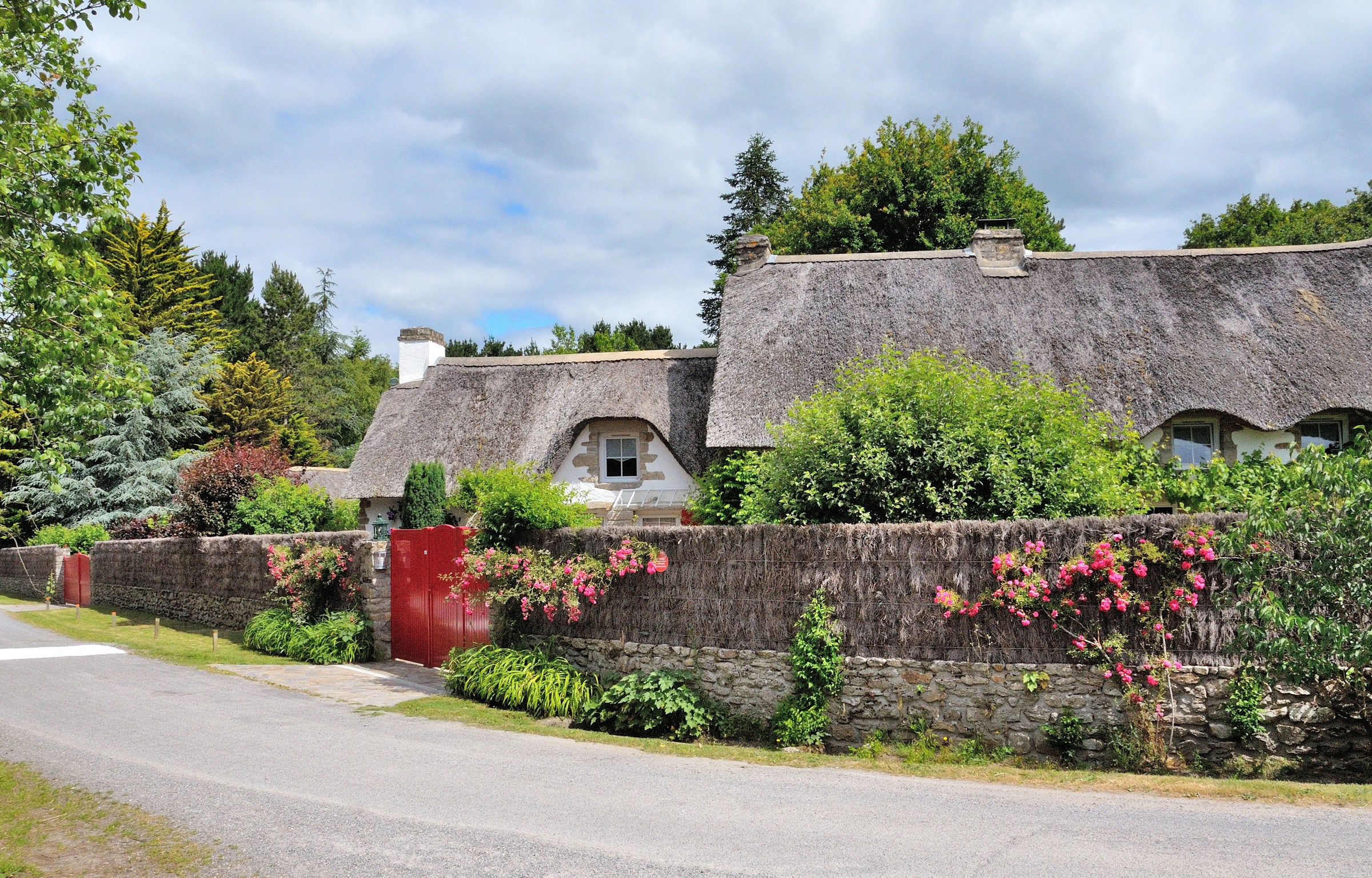 Thatched roof houses with red gates in Saint-Lyphard, France HD Wallpaper