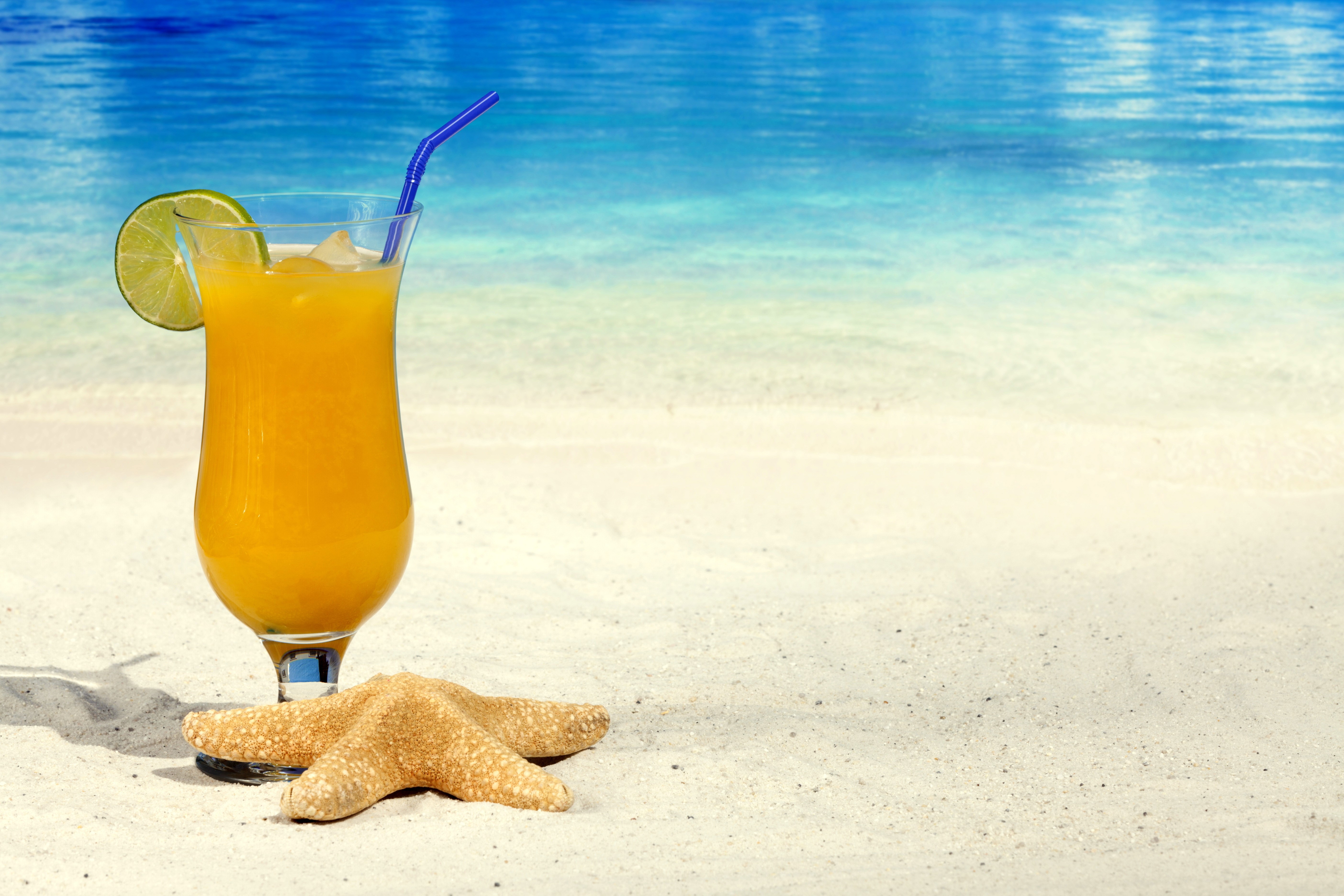 Orange juice with lime and starfish on beach HD Wallpaper
