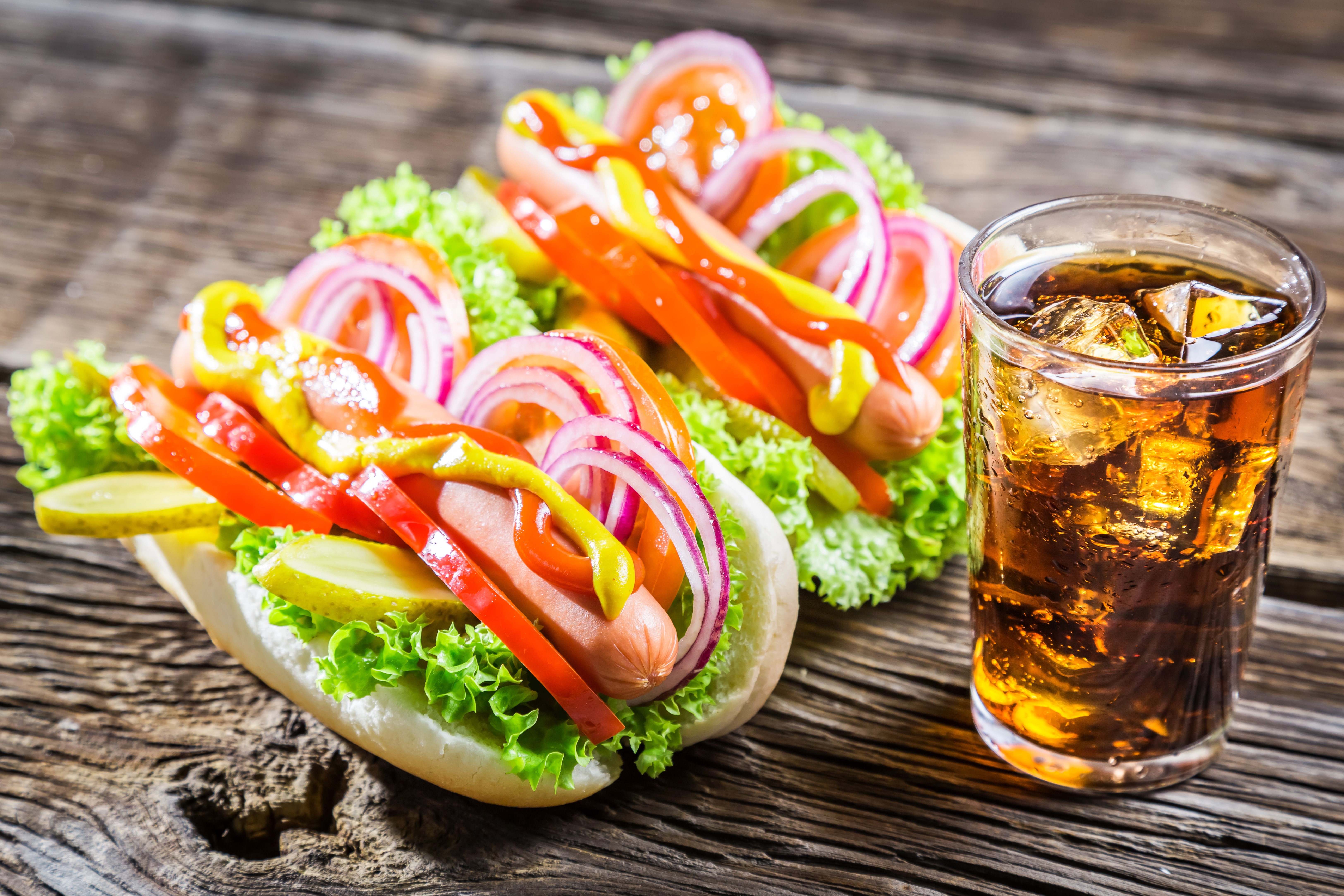 Two hot dogs with toppings and a glass of cola HD Wallpaper
