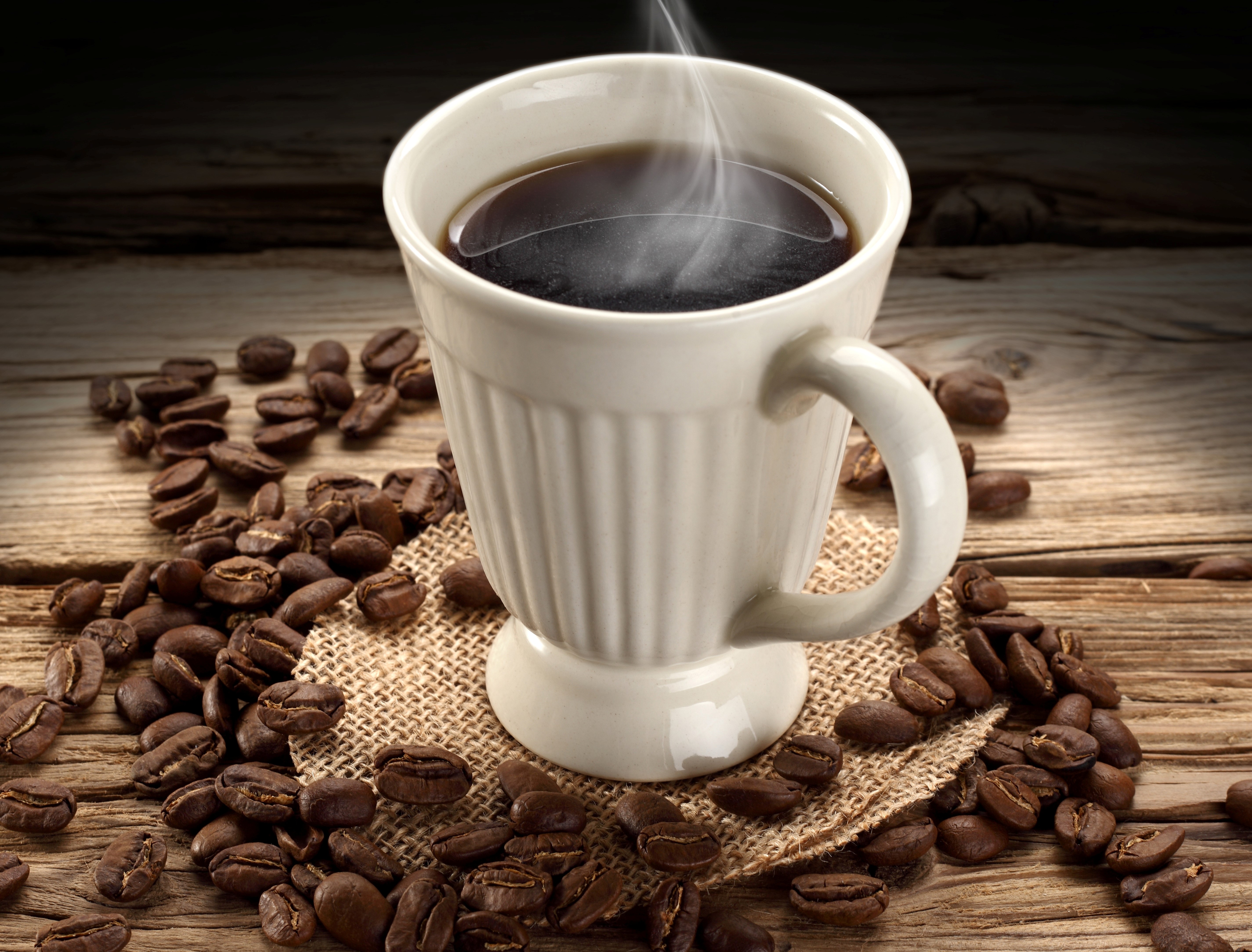 Hot coffee in a white cup with coffee beans HD Wallpaper