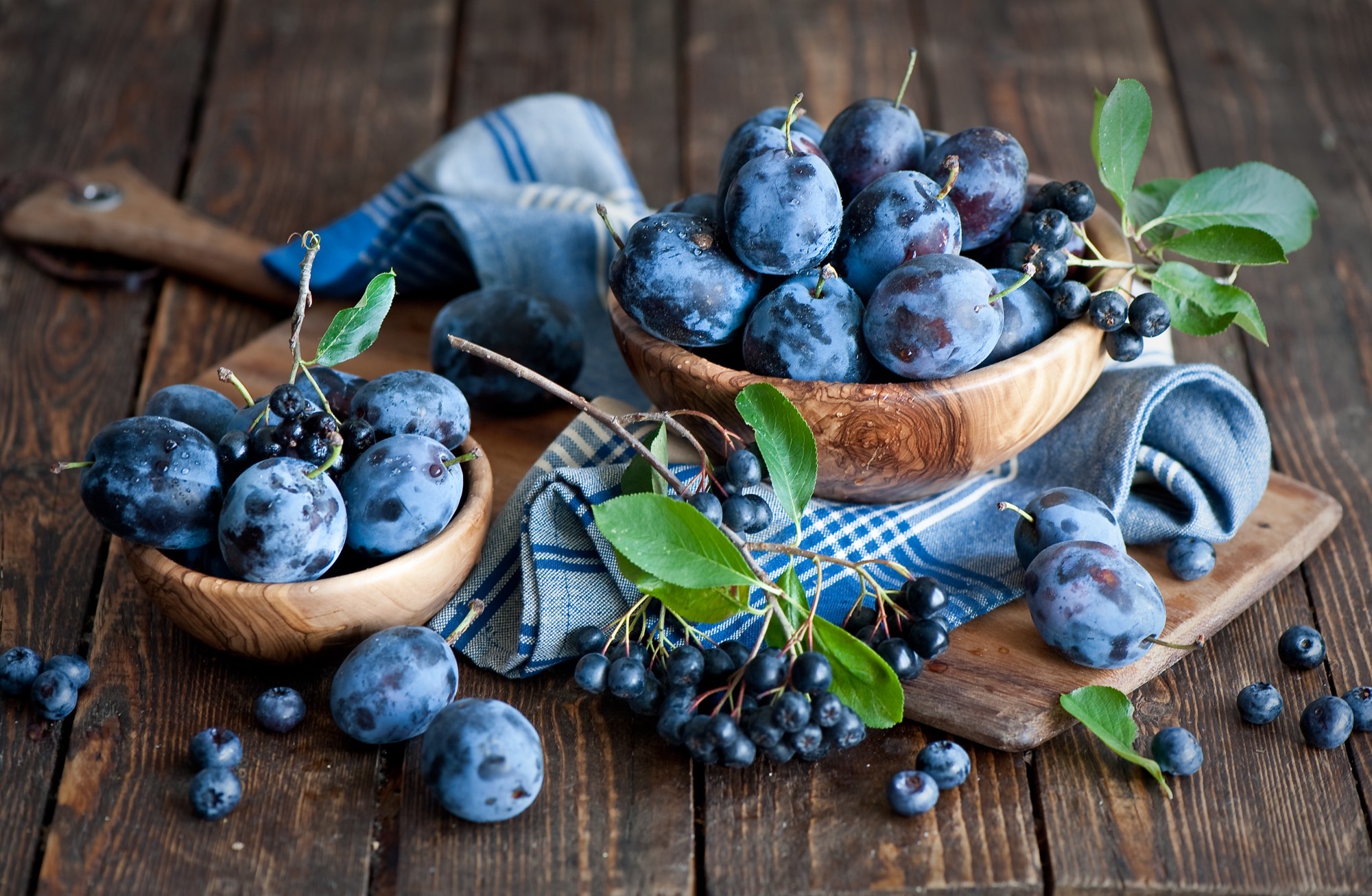 Plums and Aronia berries in wooden bowls HD Wallpaper