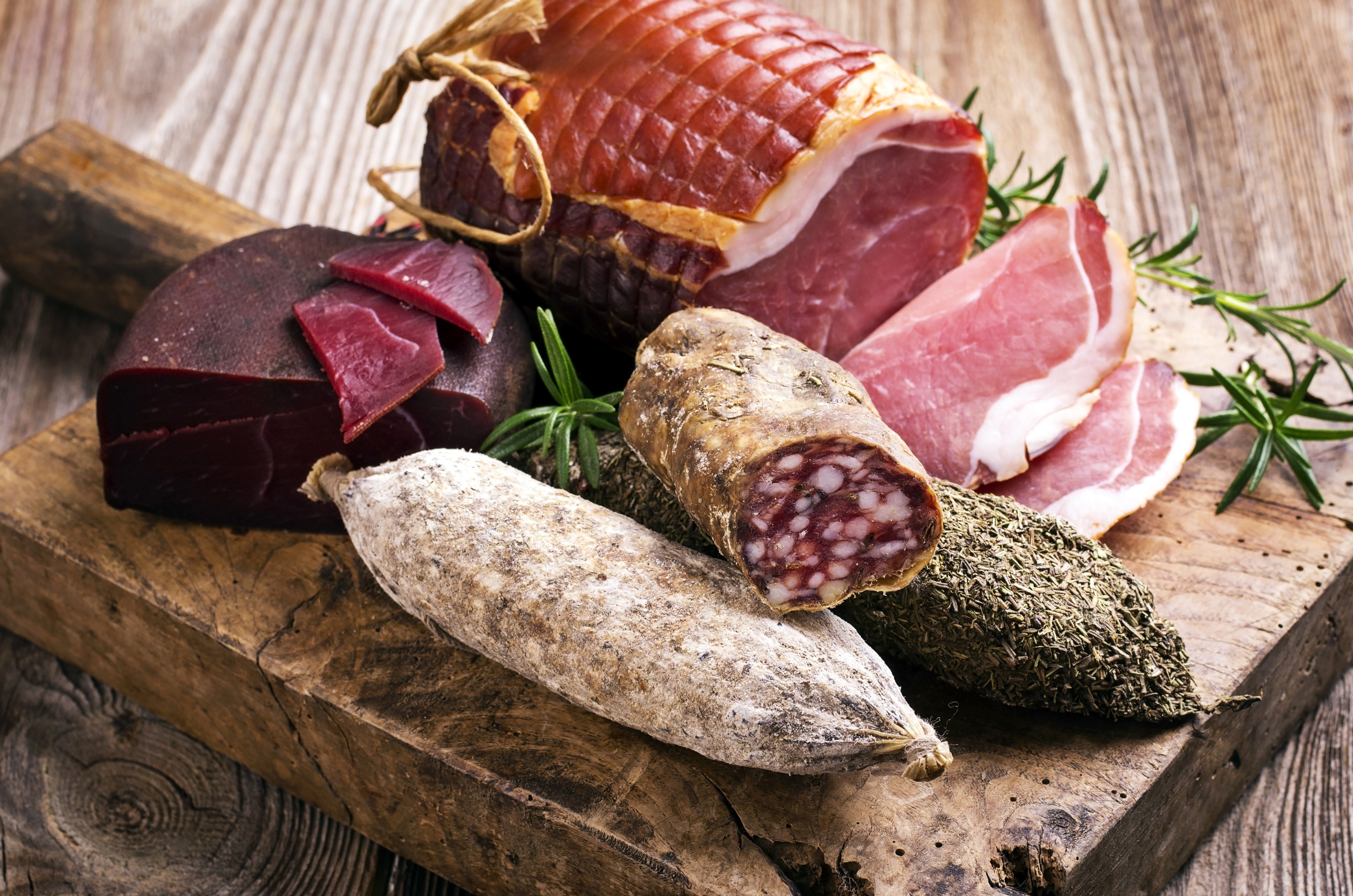 Meat products, sausage, ham, and rosemary on a wooden board HD Wallpaper