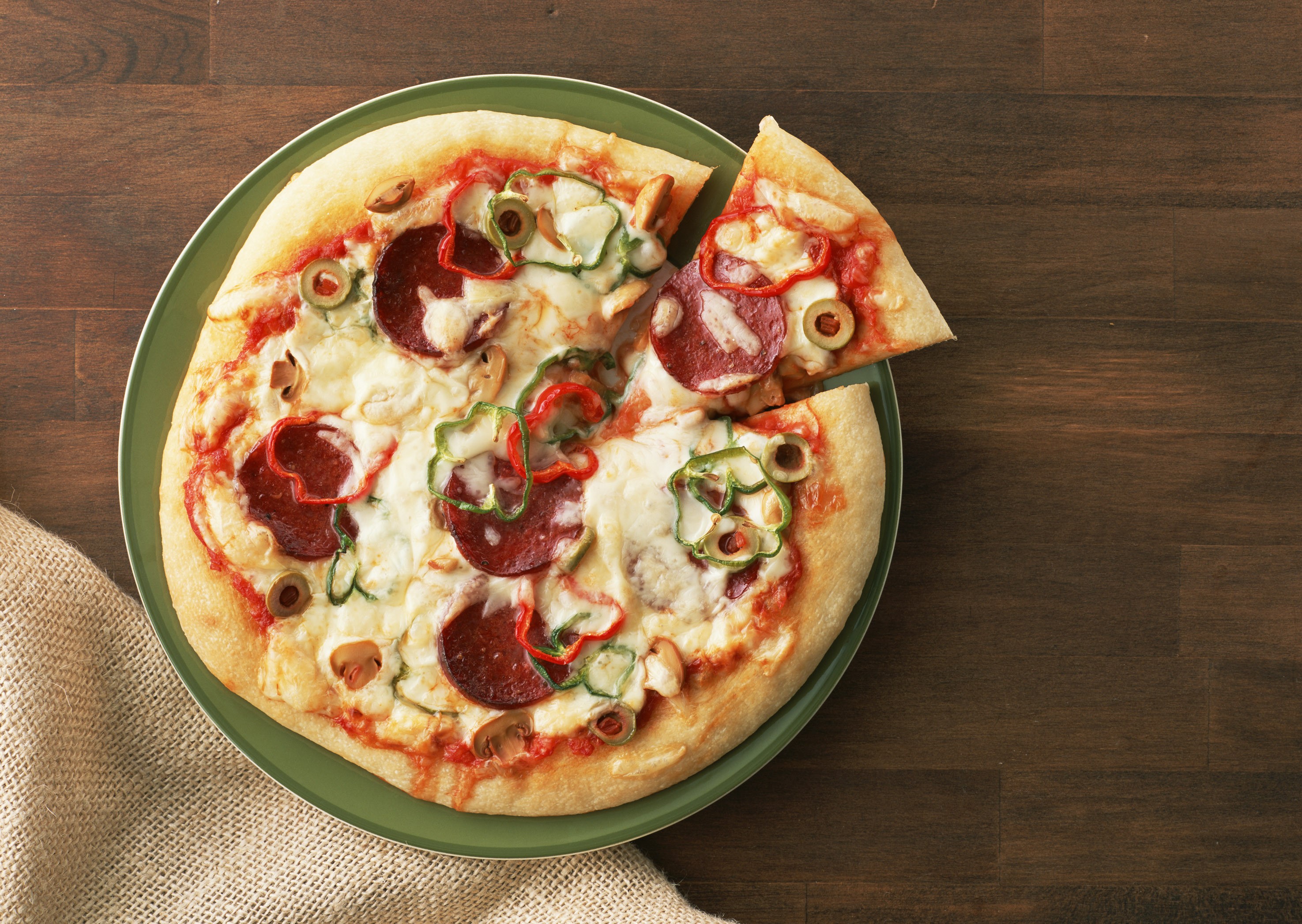 Pizza with pepperoni, peppers, and olives on a plate HD Wallpaper