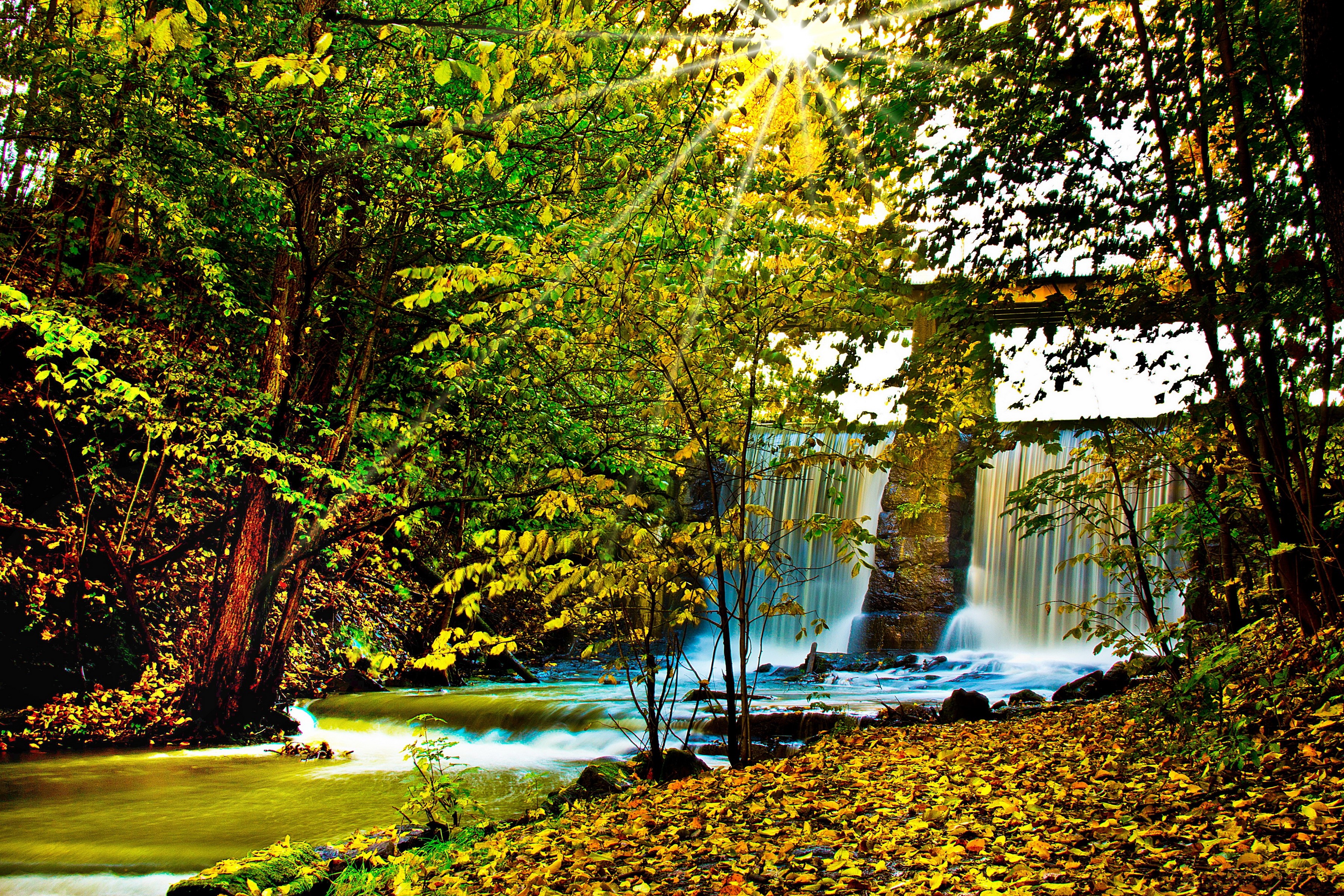 Autumn waterfall with sun rays through trees HD Wallpaper