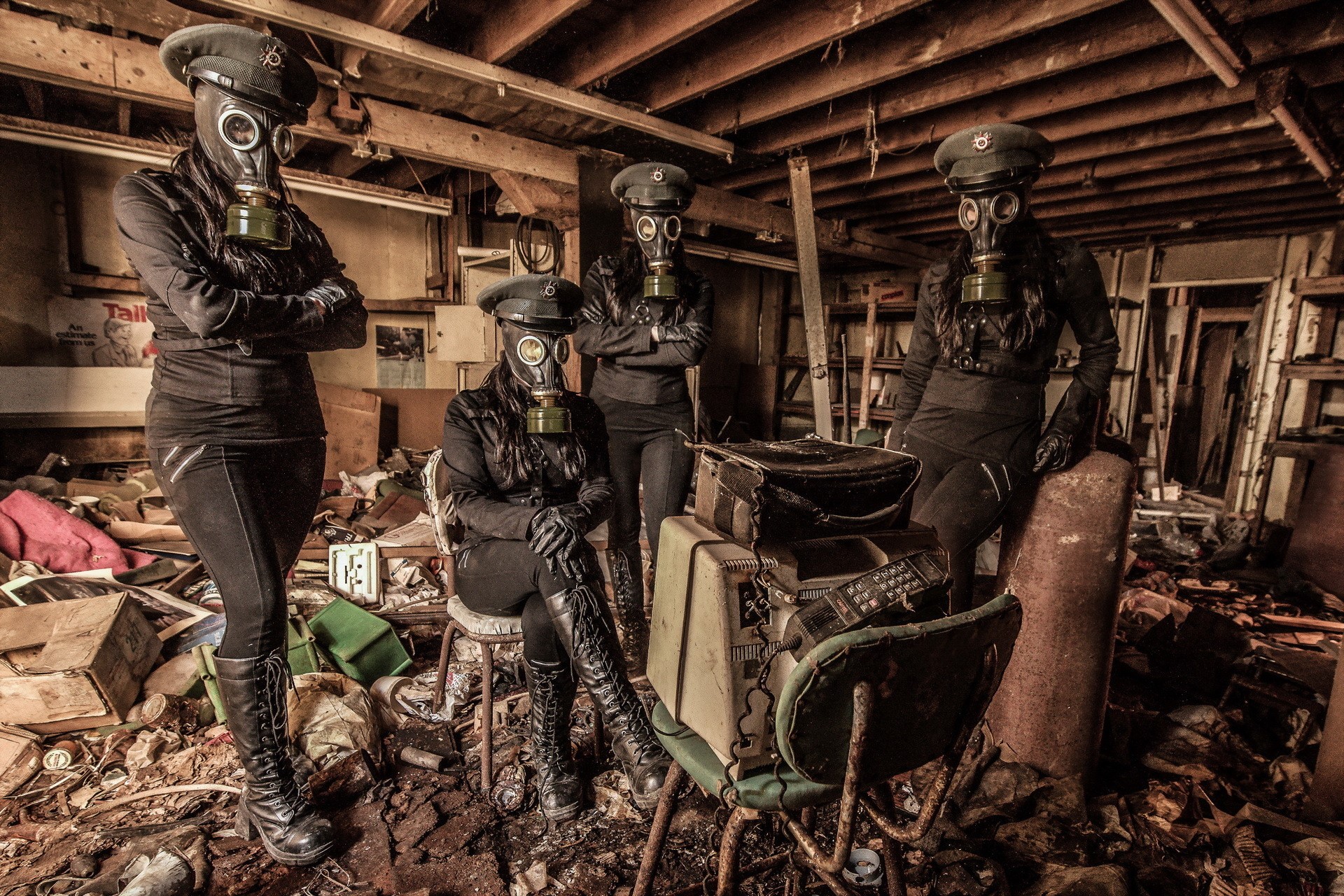 Four people in gas masks and military caps in a derelict room HD Wallpaper