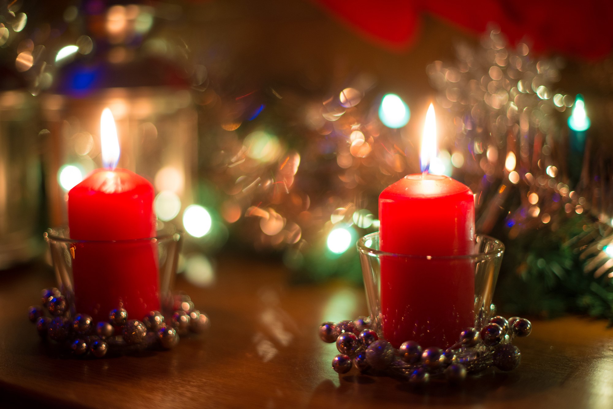 Two red candles with Christmas lights HD Wallpaper
