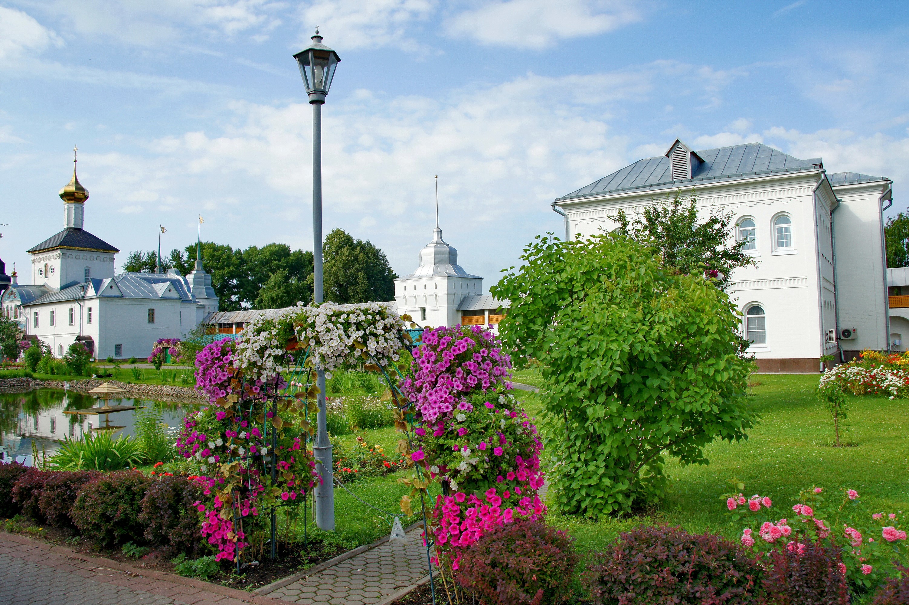 Monastery garden with blooming petunias and white buildings HD Wallpaper