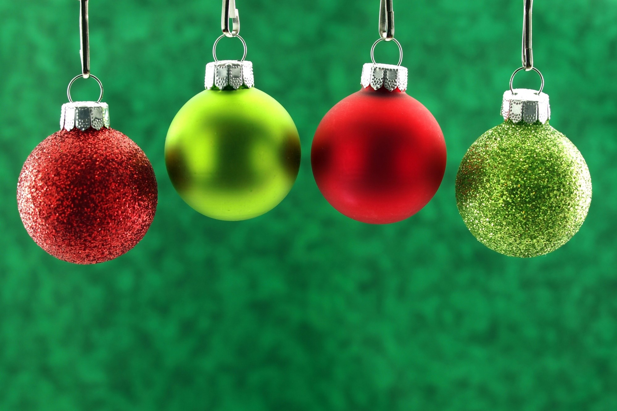 Four Christmas ornaments hanging on a green background HD Wallpaper