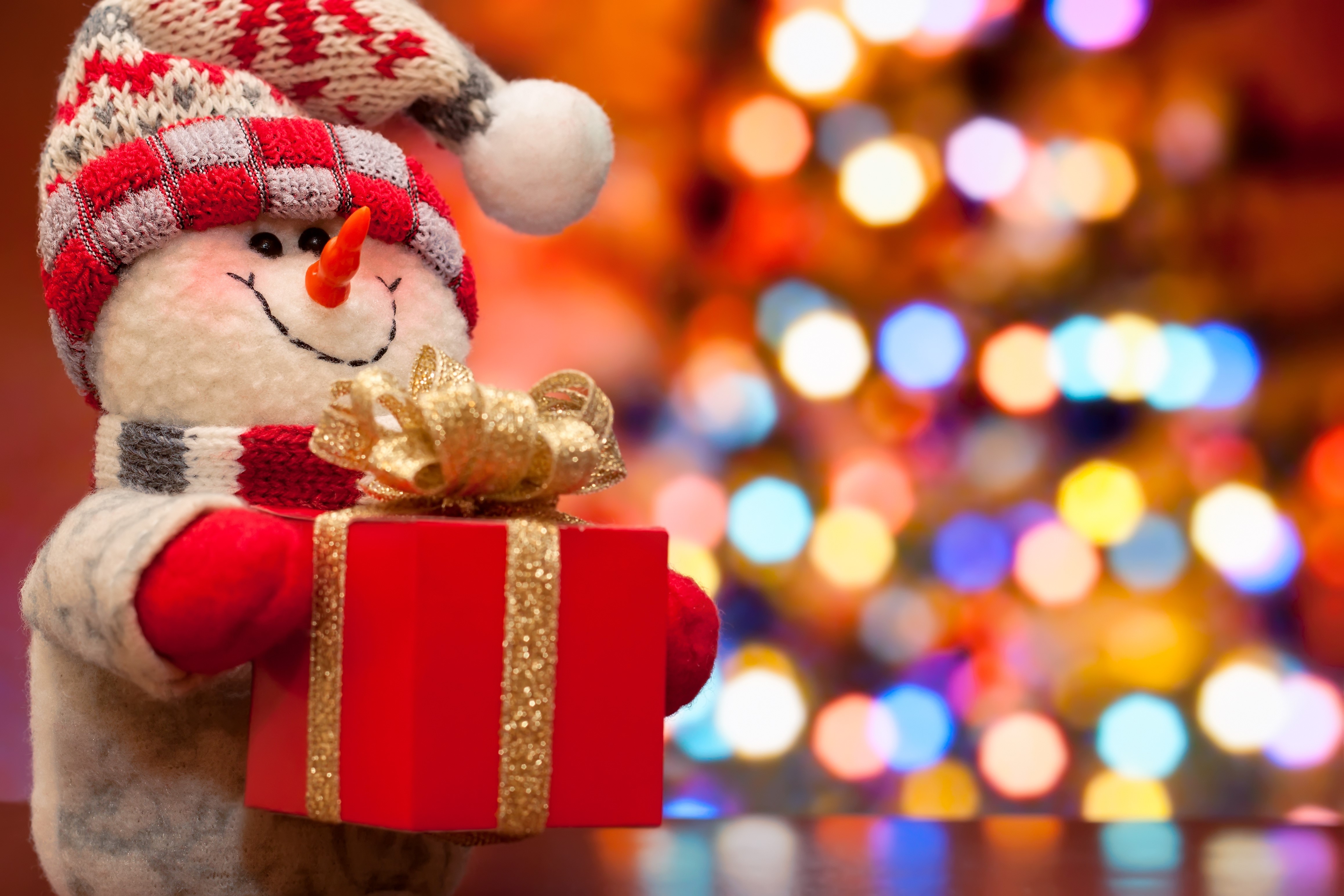 Snowman holding a Christmas gift with bokeh lights HD Wallpaper