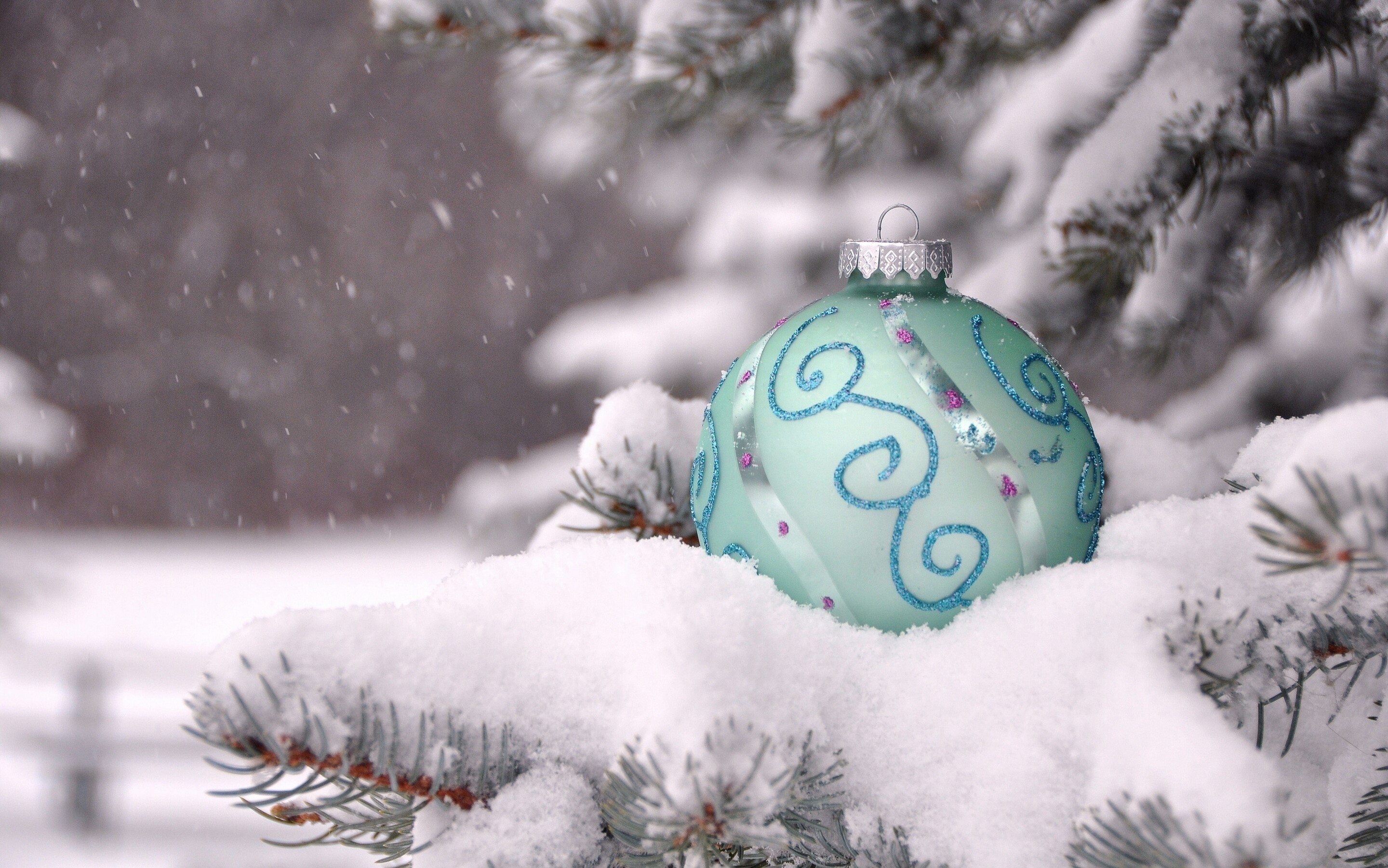 Christmas ornament on a snow-covered pine branch HD Wallpaper